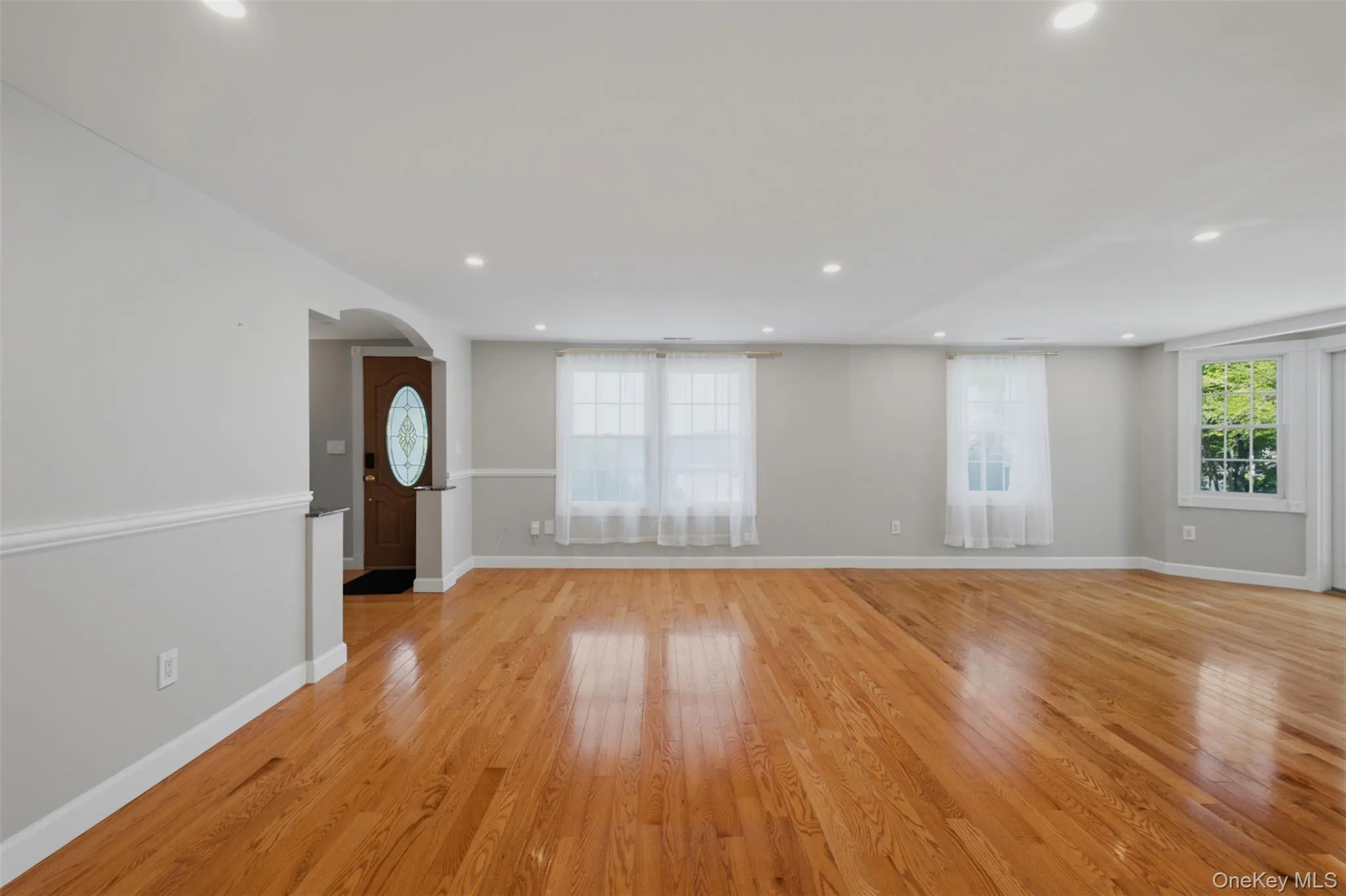 Spacious family room area featuring wood-finish flooring, recessed lighting, and a neutral color palette Spacious family room area featuring wood-finish flooring, recessed lighting, and a neutral color palette