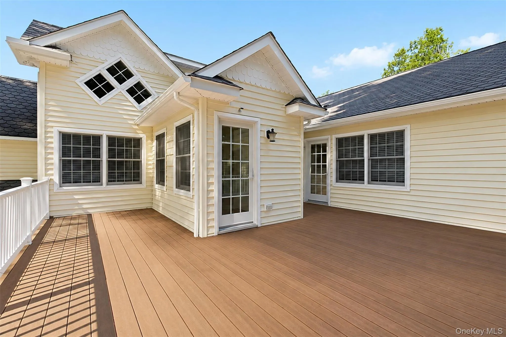 Expansive outdoor deck featuring wood-finish flooring and white railing Expansive outdoor deck featuring wood-finish flooring and white railing