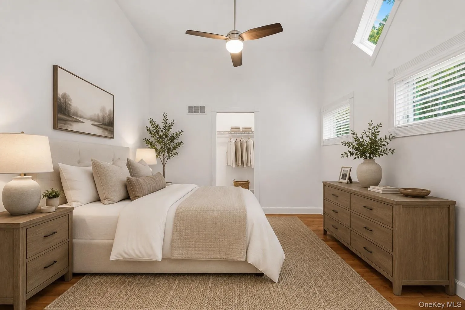 Vaulted ceiling bedroom 2 on the first level featuring wood-finish flooring, a ceiling fan with integrated lighting, and multiple windows including two skylights Vaulted ceiling bedroom 2 on the first level featuring wood-finish flooring, a ceiling fan with integrated lighting, and multiple windows including two skylights
