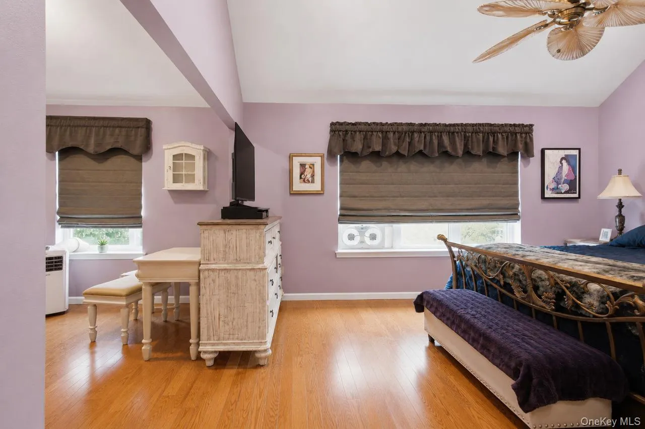 Spacious room featuring vaulted ceilings, wood-finish flooring, and multiple windows with window treatments Spacious room featuring vaulted ceilings, wood-finish flooring, and multiple windows with window treatments