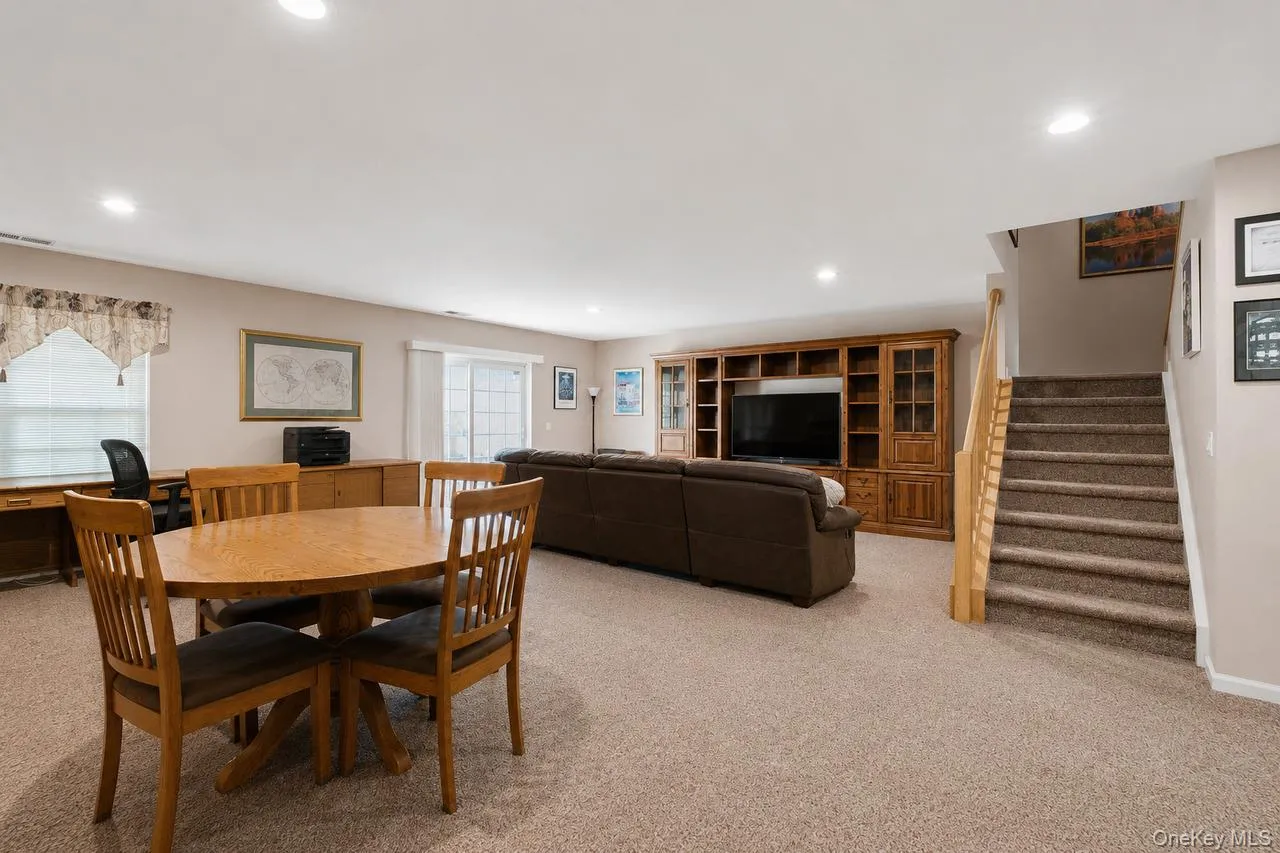 Spacious recreation area featuring neutral carpeting, a built-in entertainment center, recessed lighting, and a sliding glass door Spacious recreation area featuring neutral carpeting, a built-in entertainment center, recessed lighting, and a sliding glass door