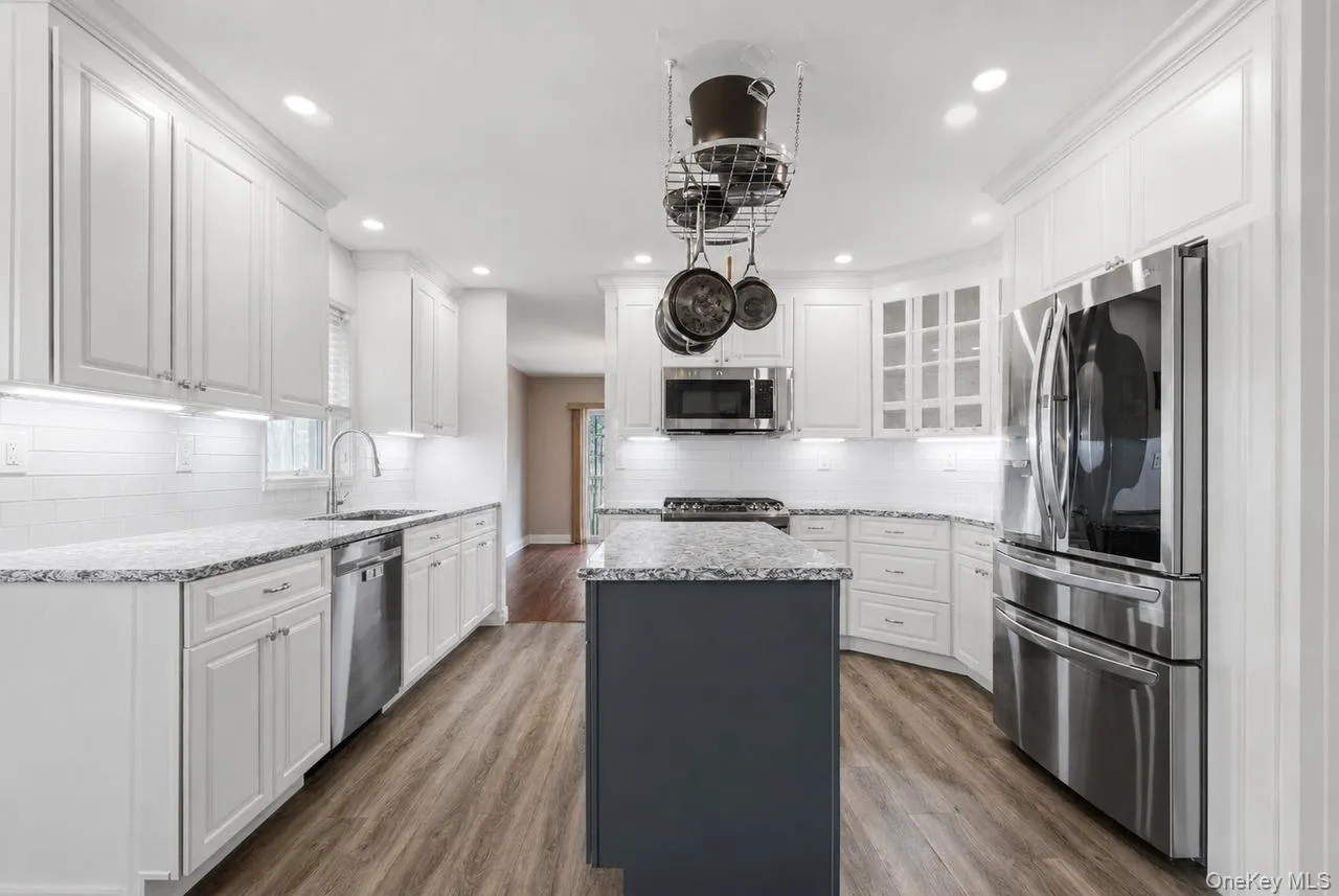 Well-appointed kitchen featuring white cabinetry and a contrasting dark-toned center island Well-appointed kitchen featuring white cabinetry and a contrasting dark-toned center island