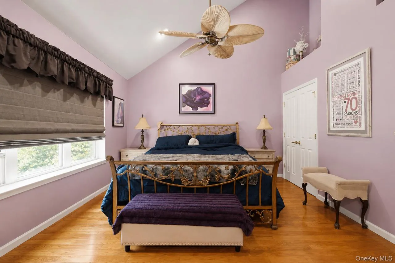 Vaulted ceiling bedroom featuring wood-finish flooring, a ceiling fan with integrated lighting, and dual windows Vaulted ceiling bedroom featuring wood-finish flooring, a ceiling fan with integrated lighting, and dual windows