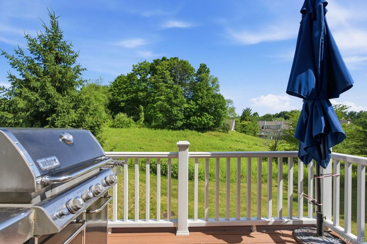 Spacious outdoor deck with composite decking, white railing system, and lush green landscaping Spacious outdoor deck with composite decking, white railing system, and lush green landscaping