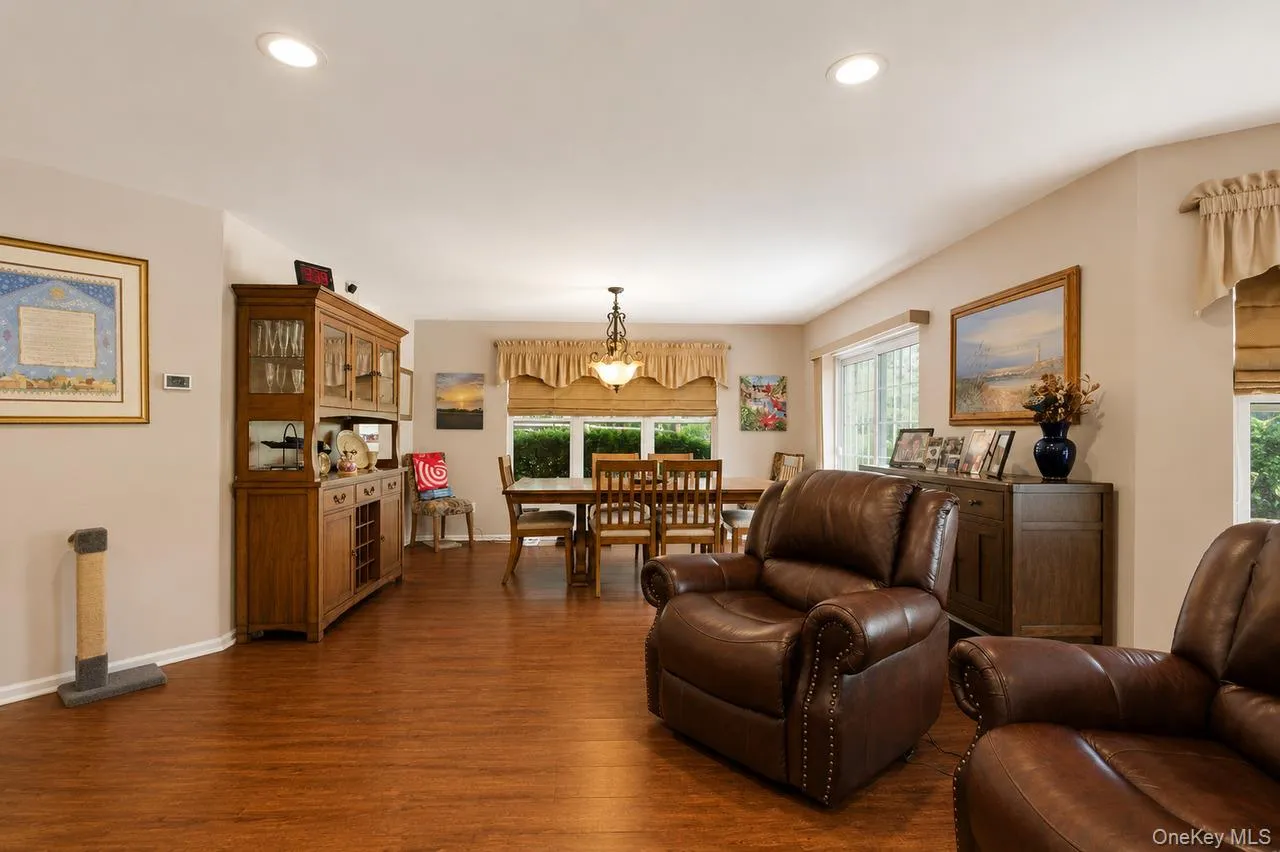 Open-concept living area featuring wood-finish flooring, recessed lighting, and ample natural light from multiple windows Open-concept living area featuring wood-finish flooring, recessed lighting, and ample natural light from multiple windows
