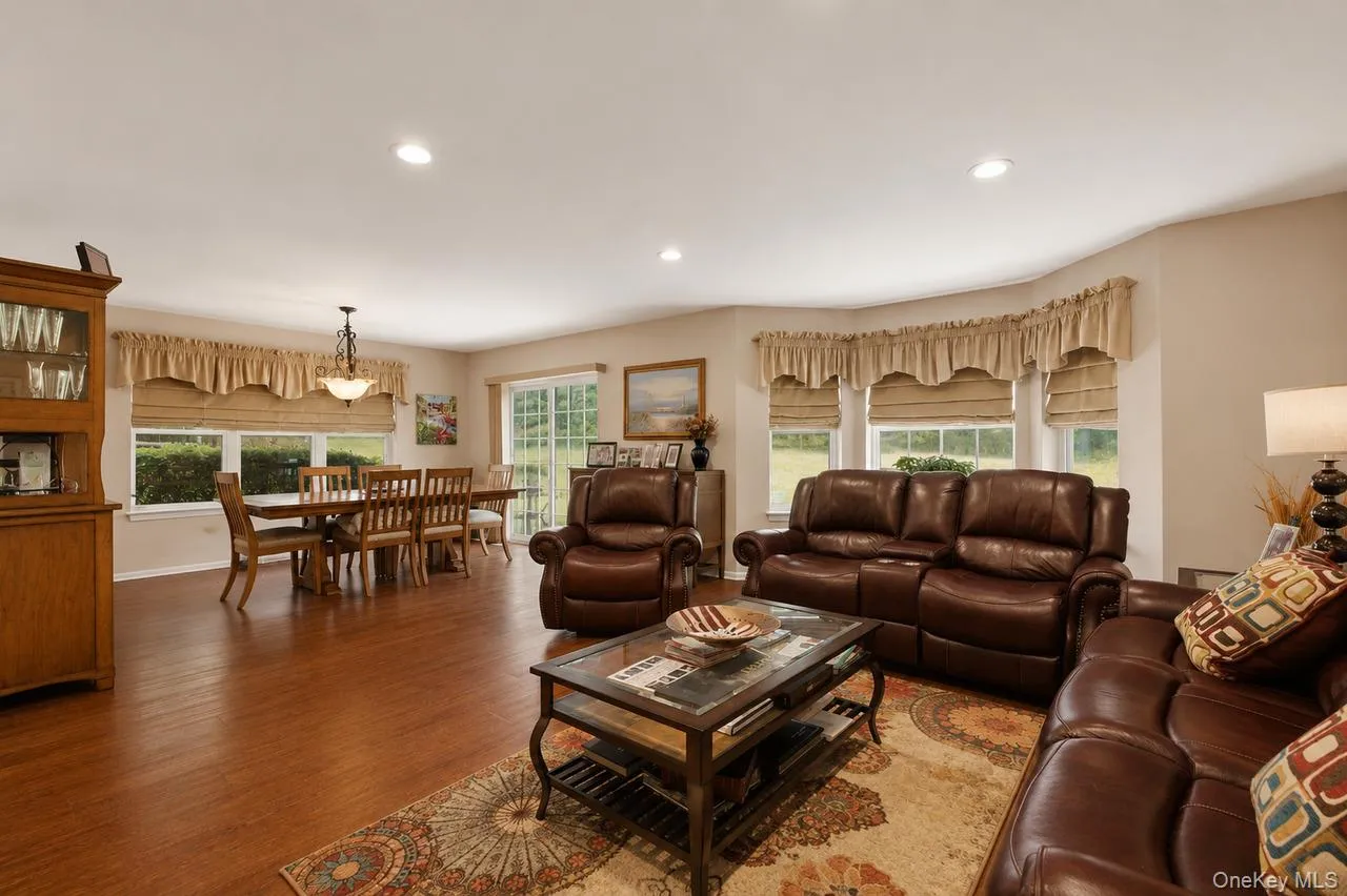 Expansive room with wood-finish flooring, recessed lighting, and neutral wall tones Expansive room with wood-finish flooring, recessed lighting, and neutral wall tones
