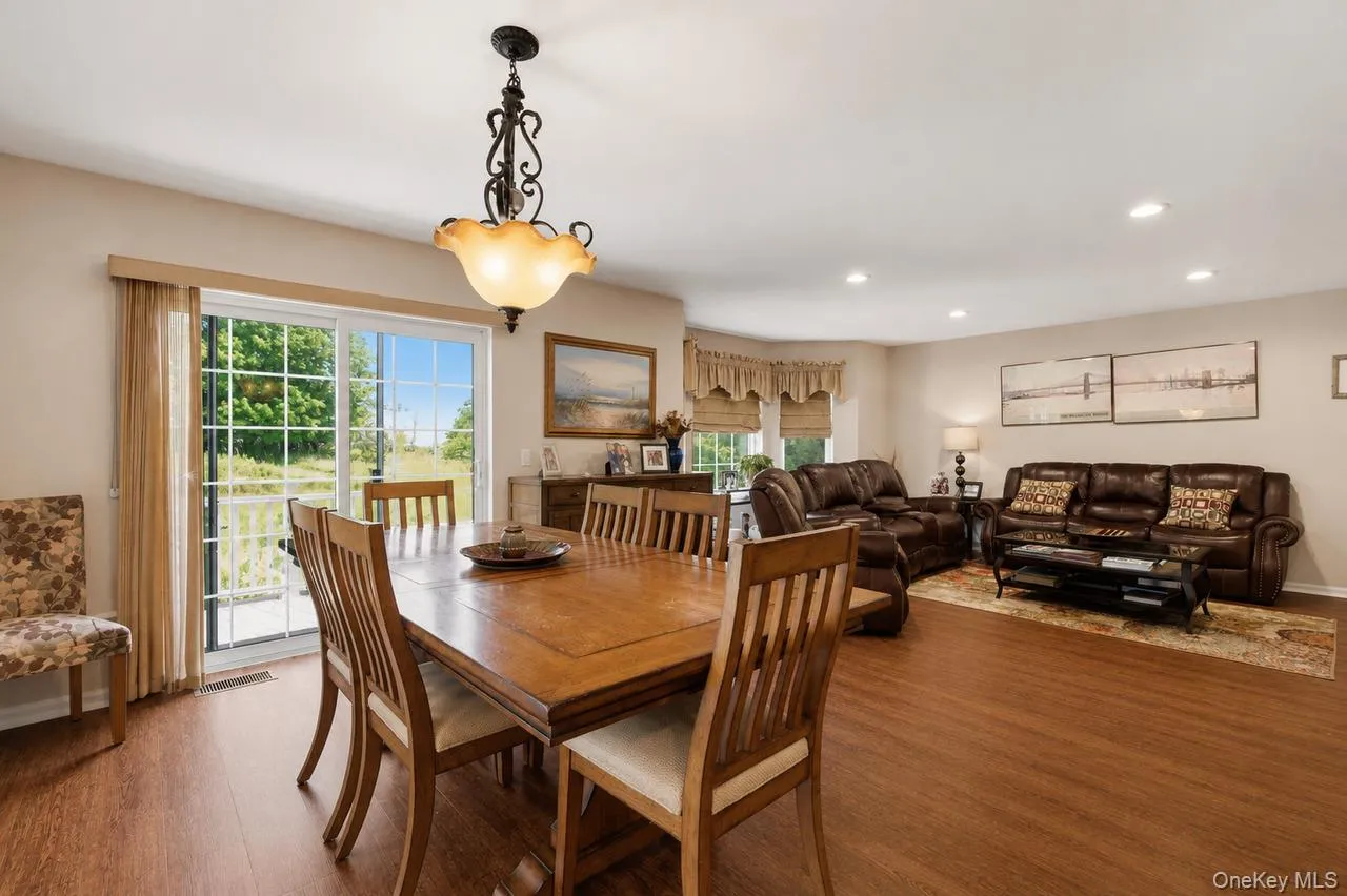 Spacious dining area featuring a wood-finish dining table, chandelier lighting, and a sliding glass door providing outdoor access Spacious dining area featuring a wood-finish dining table, chandelier lighting, and a sliding glass door providing outdoor access