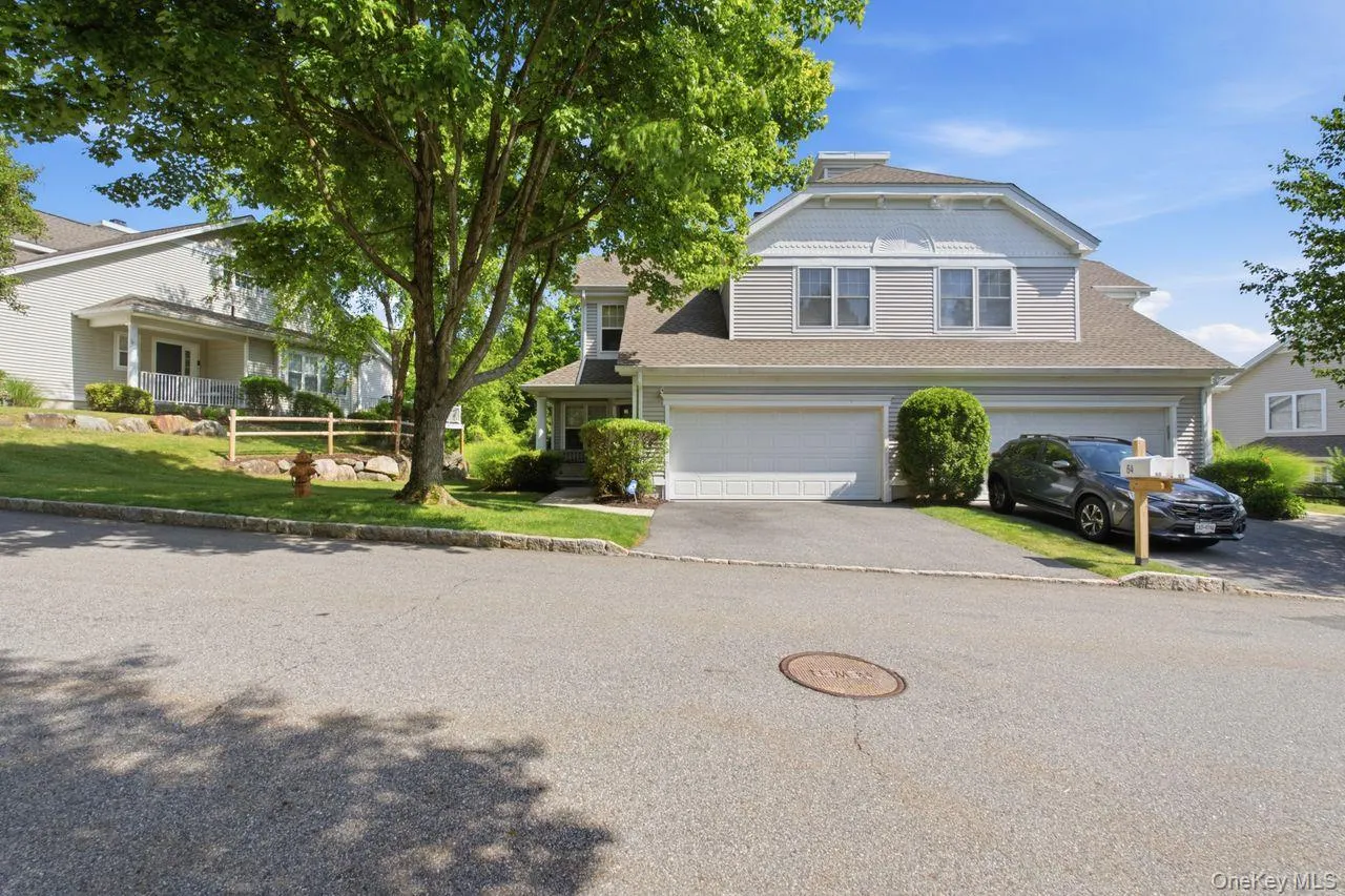 Contemporary exterior featuring light grey siding, a two-car garage, and a sloped driveway Contemporary exterior featuring light grey siding, a two-car garage, and a sloped driveway