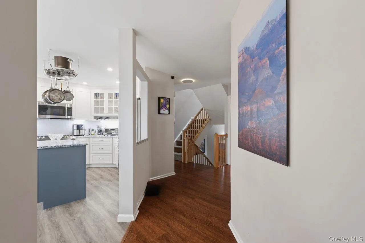 Kitchen featuring white cabinetry, stainless steel appliances, a blue-grey island with a light-colored countertop, and wood-finish flooring Kitchen featuring white cabinetry, stainless steel appliances, a blue-grey island with a light-colored countertop, and wood-finish flooring