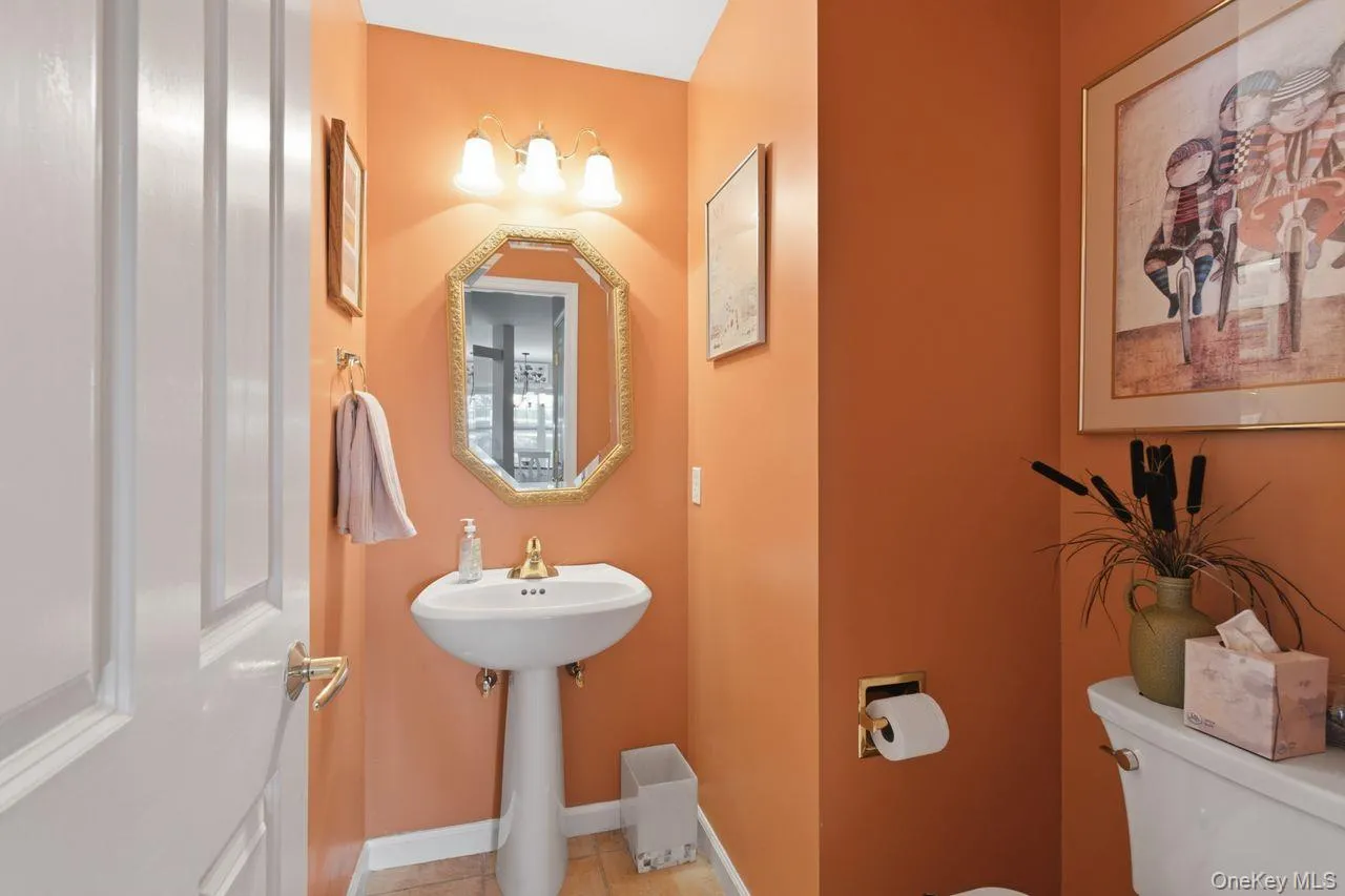 Pedestal sink with gold-tone faucet, octagonal mirror, and three-light vanity fixture Pedestal sink with gold-tone faucet, octagonal mirror, and three-light vanity fixture