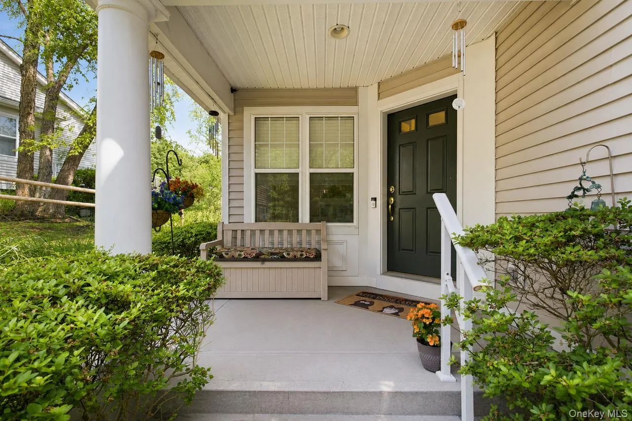 Covered front porch featuring a dark paneled entry door, light-colored siding, and white trim Covered front porch featuring a dark paneled entry door, light-colored siding, and white trim