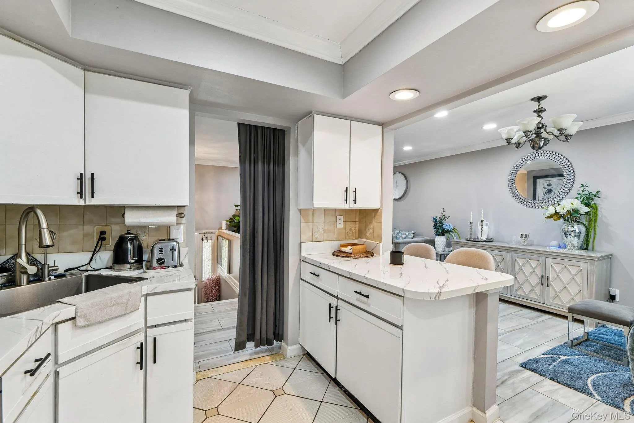 Bright kitchen featuring white cabinetry, a built-in stainless steel sink, tile backsplash, and recessed lighting Bright kitchen featuring white cabinetry, a built-in stainless steel sink, tile backsplash, and recessed lighting