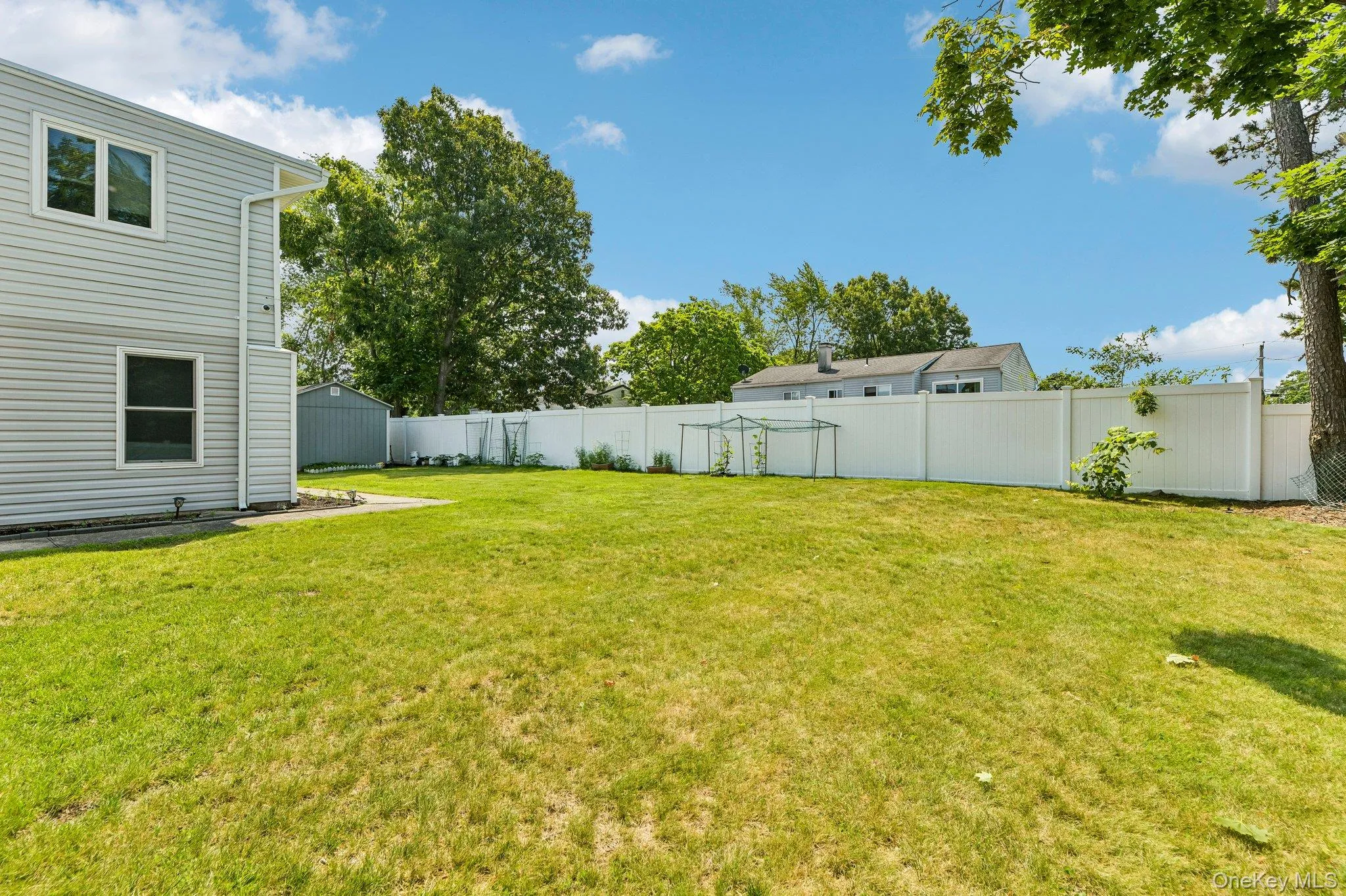 Spacious lawn area featuring a white privacy fence and a detached storage shed Spacious lawn area featuring a white privacy fence and a detached storage shed