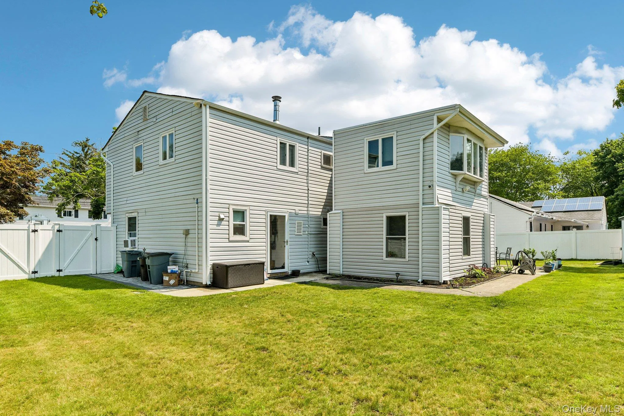 Expansive rear yard featuring green lawn, a white privacy fence, and a two-story exterior with light-colored siding Expansive rear yard featuring green lawn, a white privacy fence, and a two-story exterior with light-colored siding