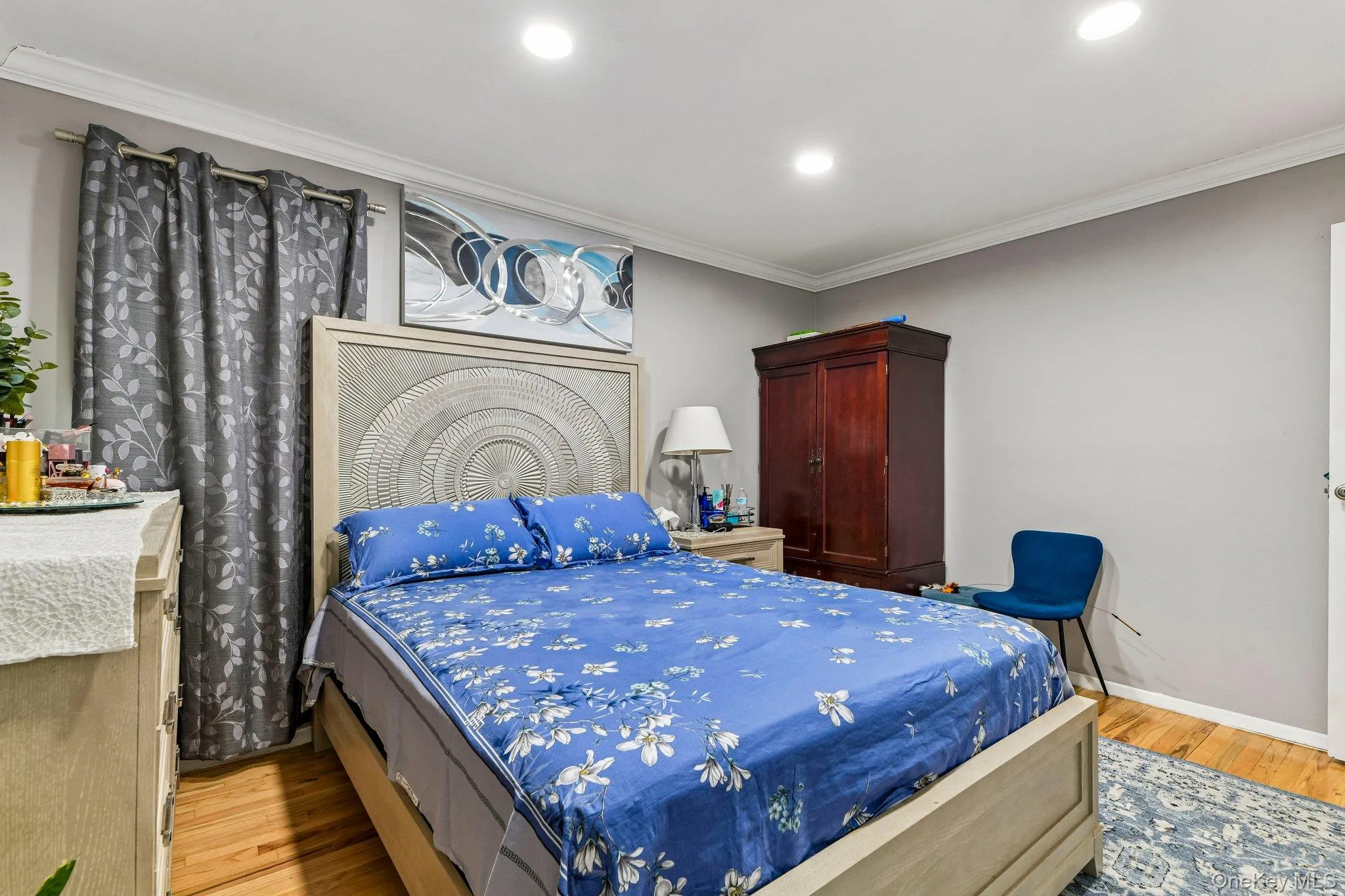 Recessed lighting illuminates this room, featuring wood-finish flooring, crown molding, and a light gray wall color Recessed lighting illuminates this room, featuring wood-finish flooring, crown molding, and a light gray wall color