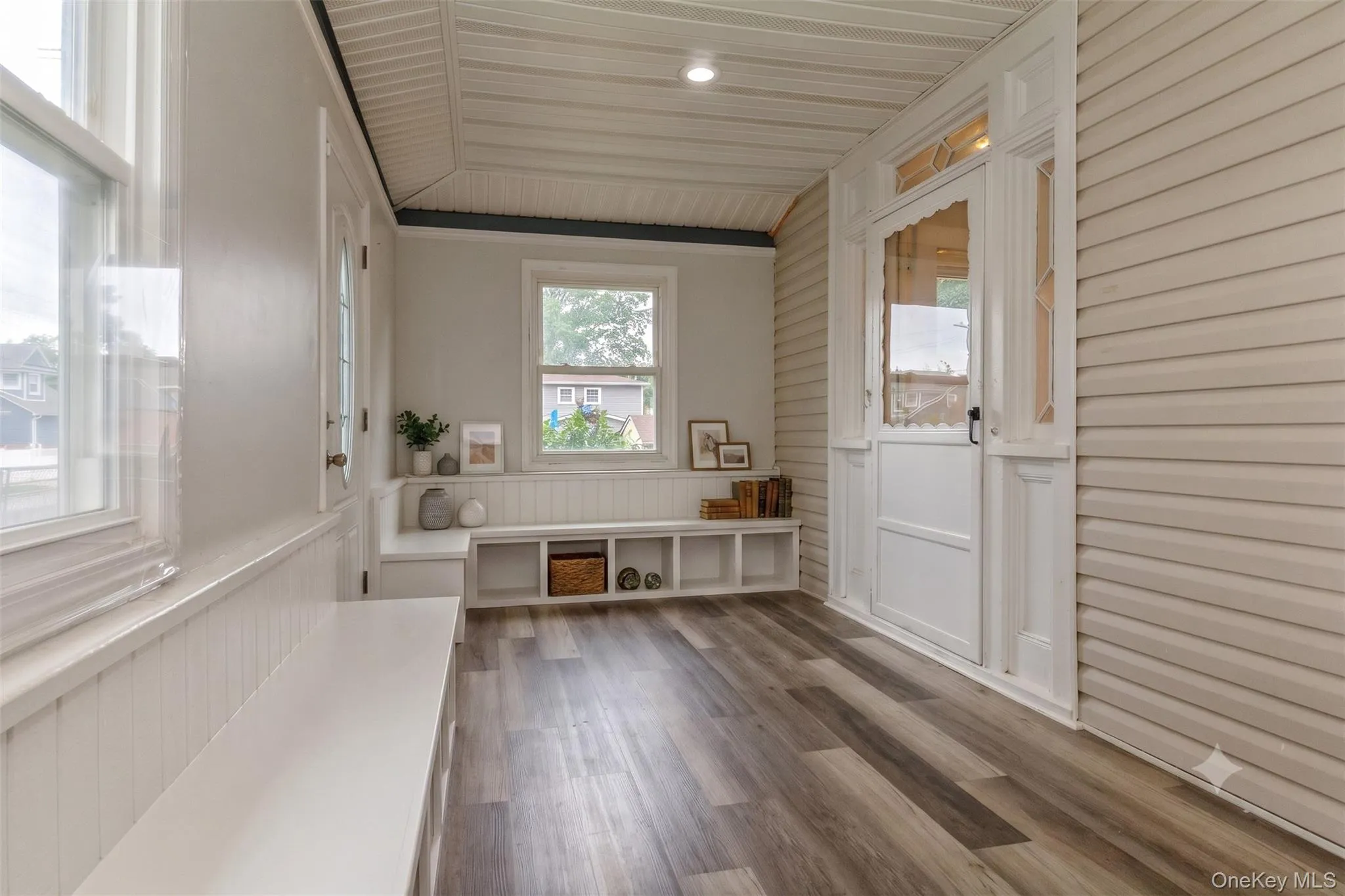 Entryway featuring wood-finish flooring, white paneled walls, and a built-in bench Entryway featuring wood-finish flooring, white paneled walls, and a built-in bench