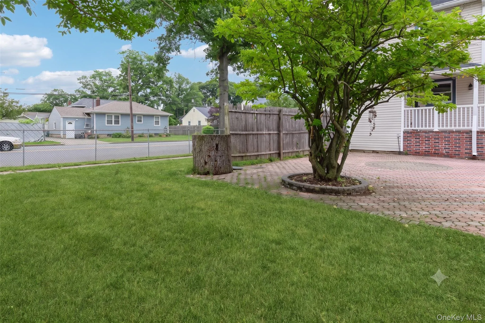 Expansive paver patio featuring a circular design, bordered by a mature tree Expansive paver patio featuring a circular design, bordered by a mature tree