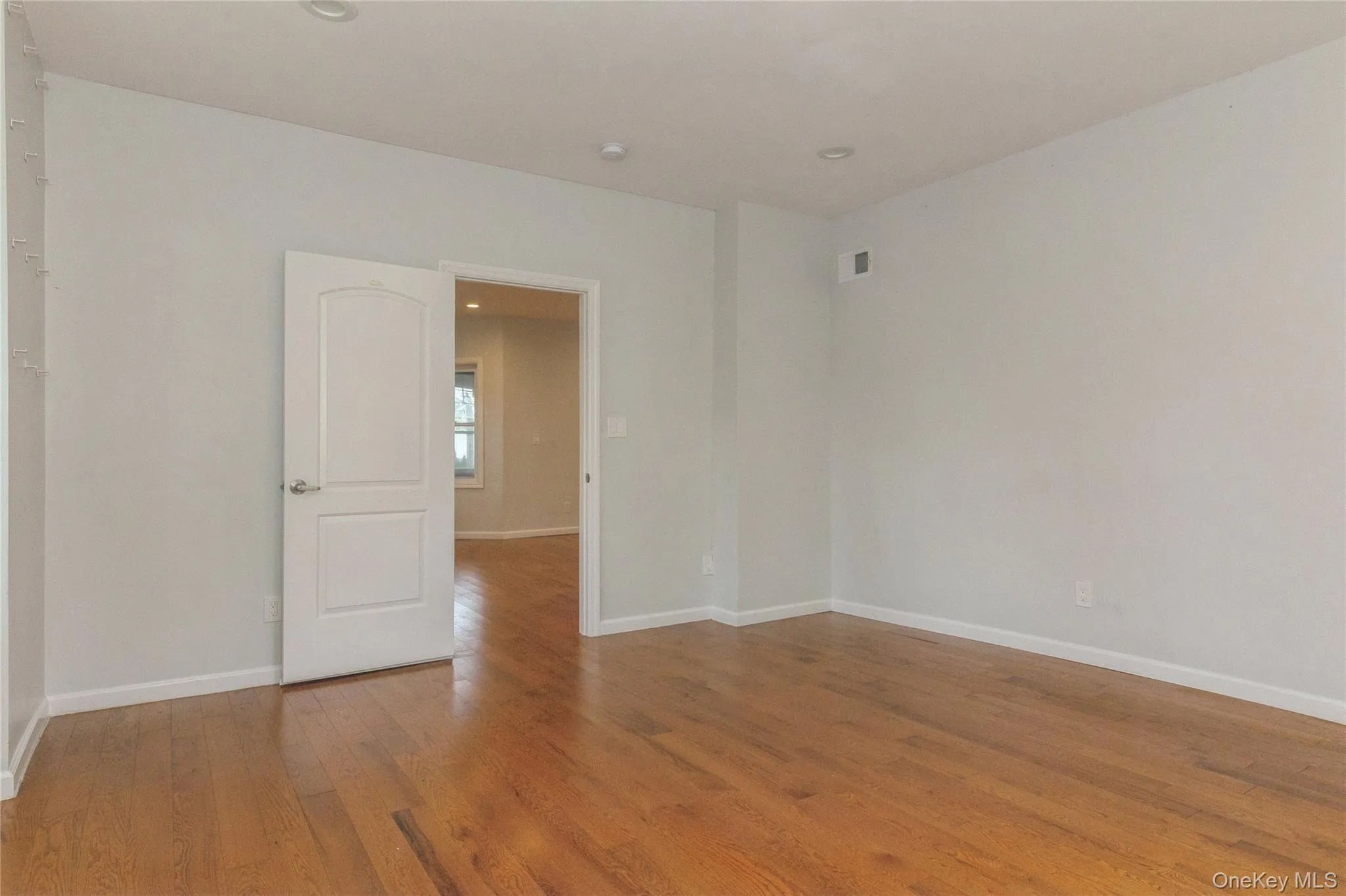 Upstairs bedroom featuring wood-finish flooring, light neutral wall tones, recessed lighting, and a paneled interior door with lever hardware Upstairs bedroom featuring wood-finish flooring, light neutral wall tones, recessed lighting, and a paneled interior door with lever hardware