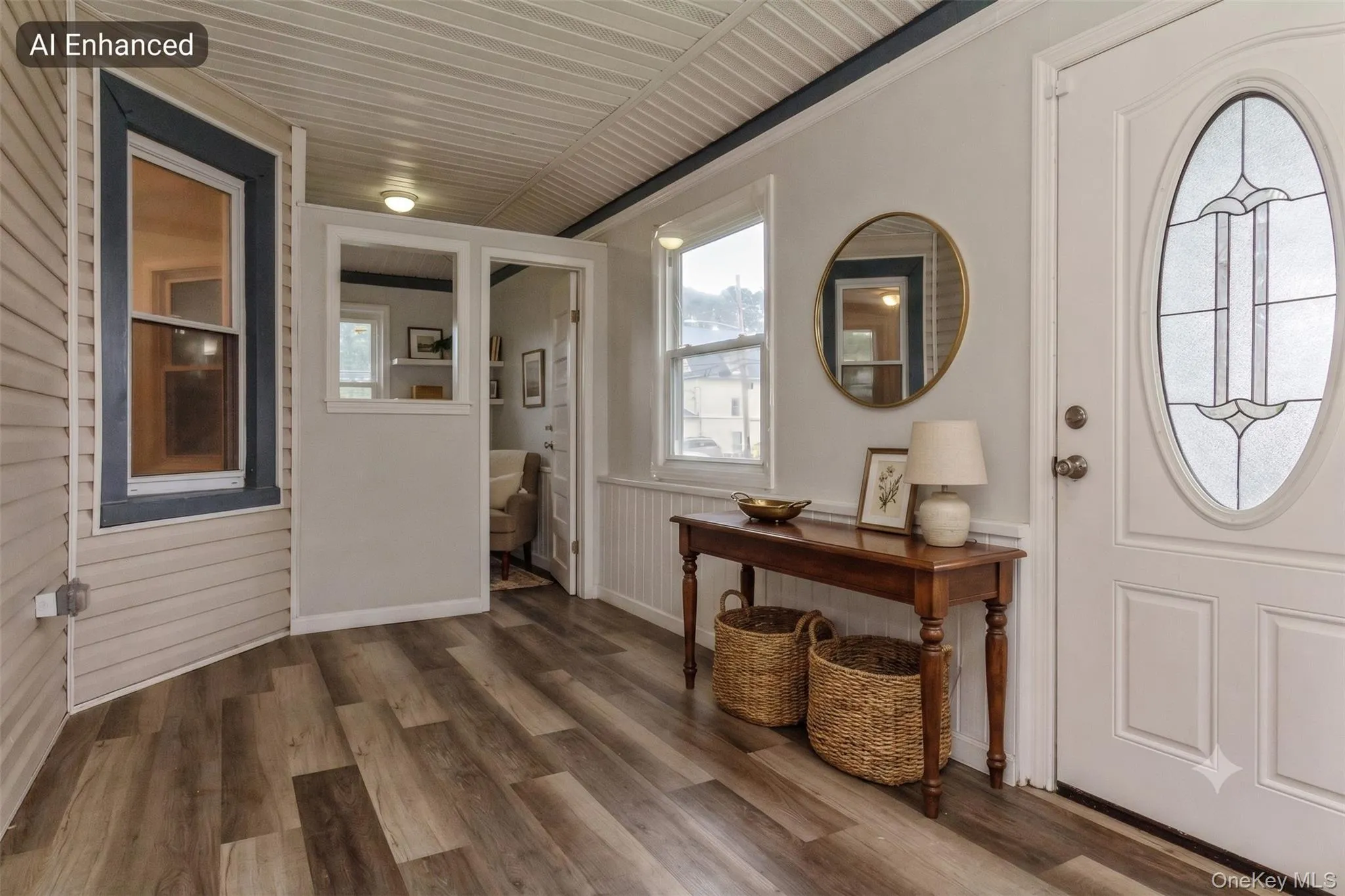 Entryway featuring a white paneled door with an oval stained-glass insert, wood-finish flooring, and white beadboard wainscoting Entryway featuring a white paneled door with an oval stained-glass insert, wood-finish flooring, and white beadboard wainscoting