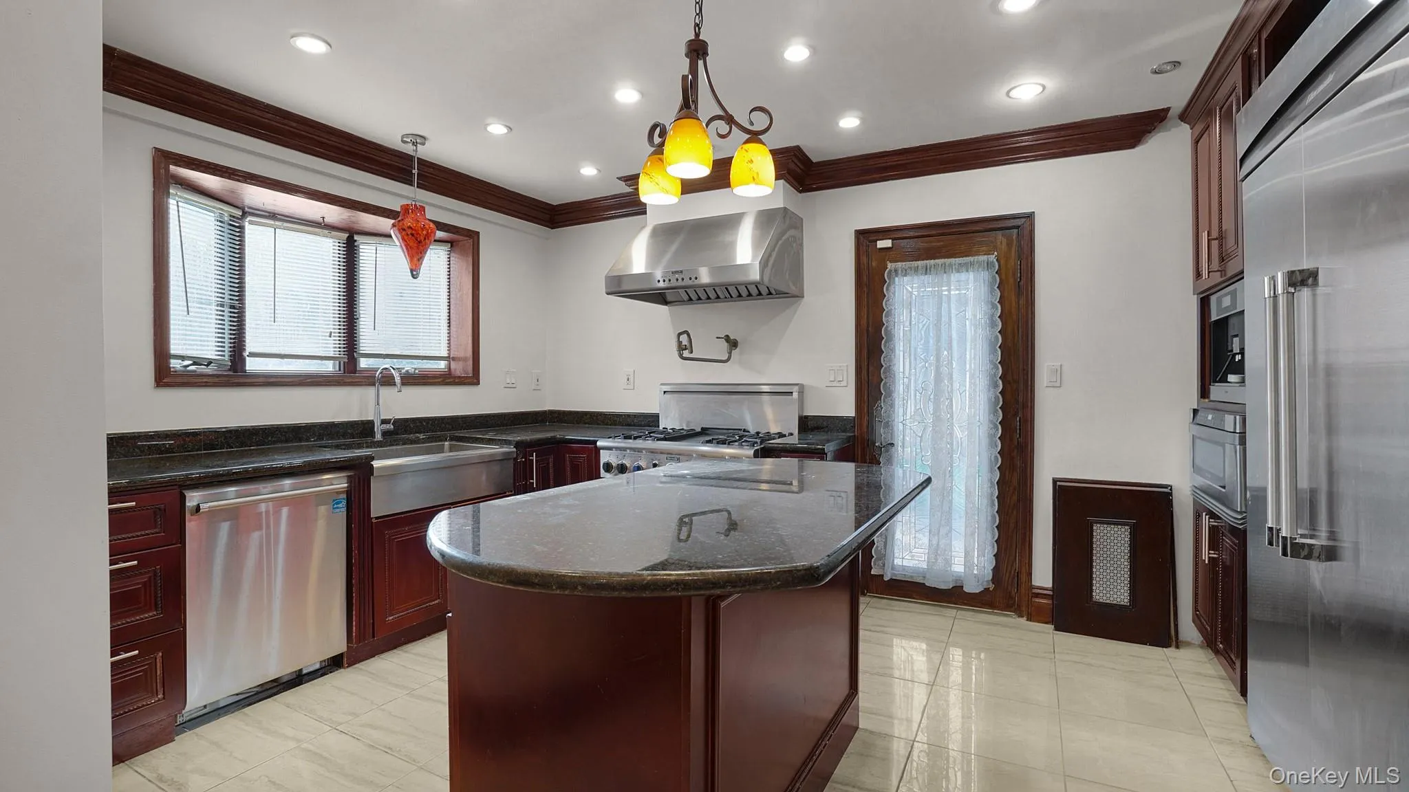 Kitchen featuring dark wood cabinetry, granite countertops, and stainless steel appliances Kitchen featuring dark wood cabinetry, granite countertops, and stainless steel appliances