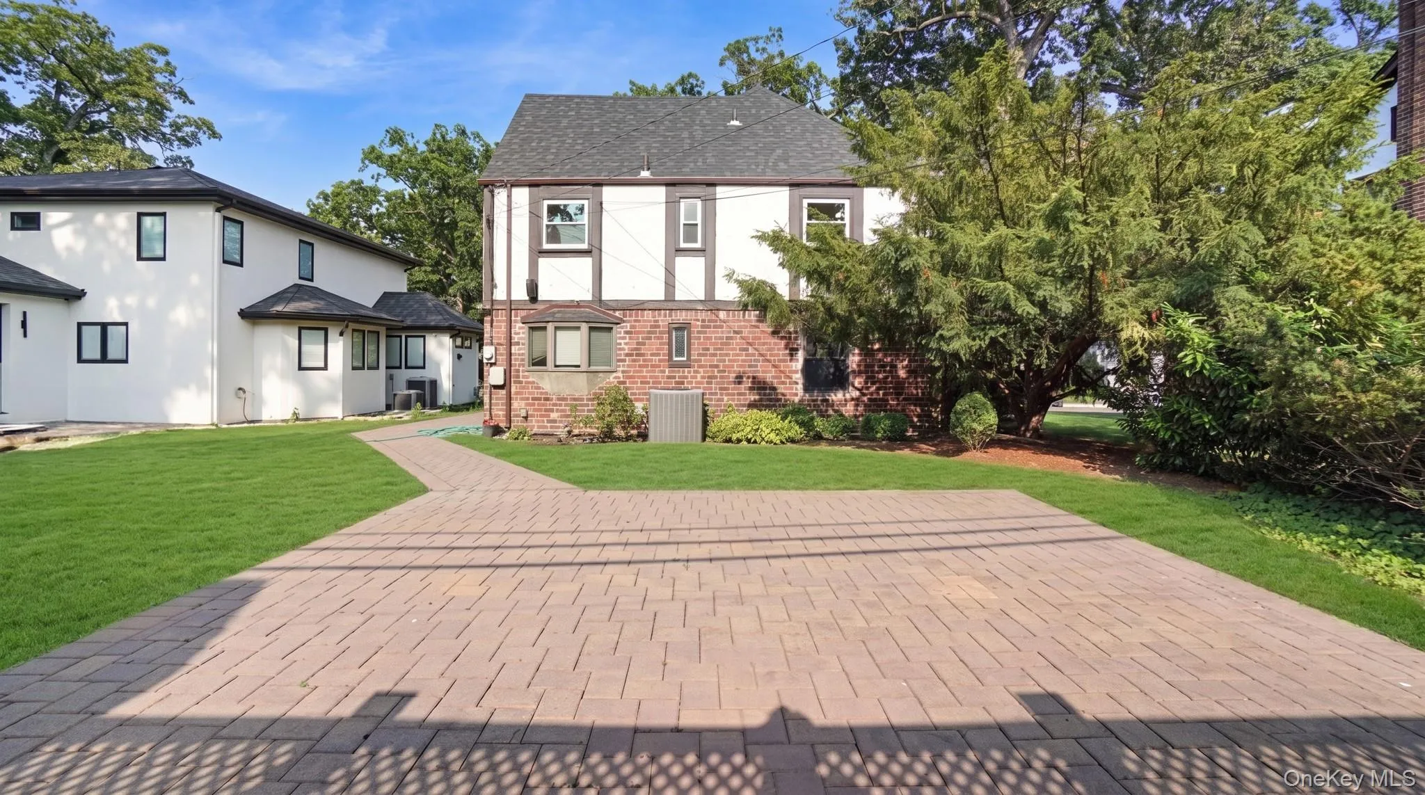 Brick paver patio with a curved paver pathway, expansive lawn, and mature perimeter landscaping Brick paver patio with a curved paver pathway, expansive lawn, and mature perimeter landscaping