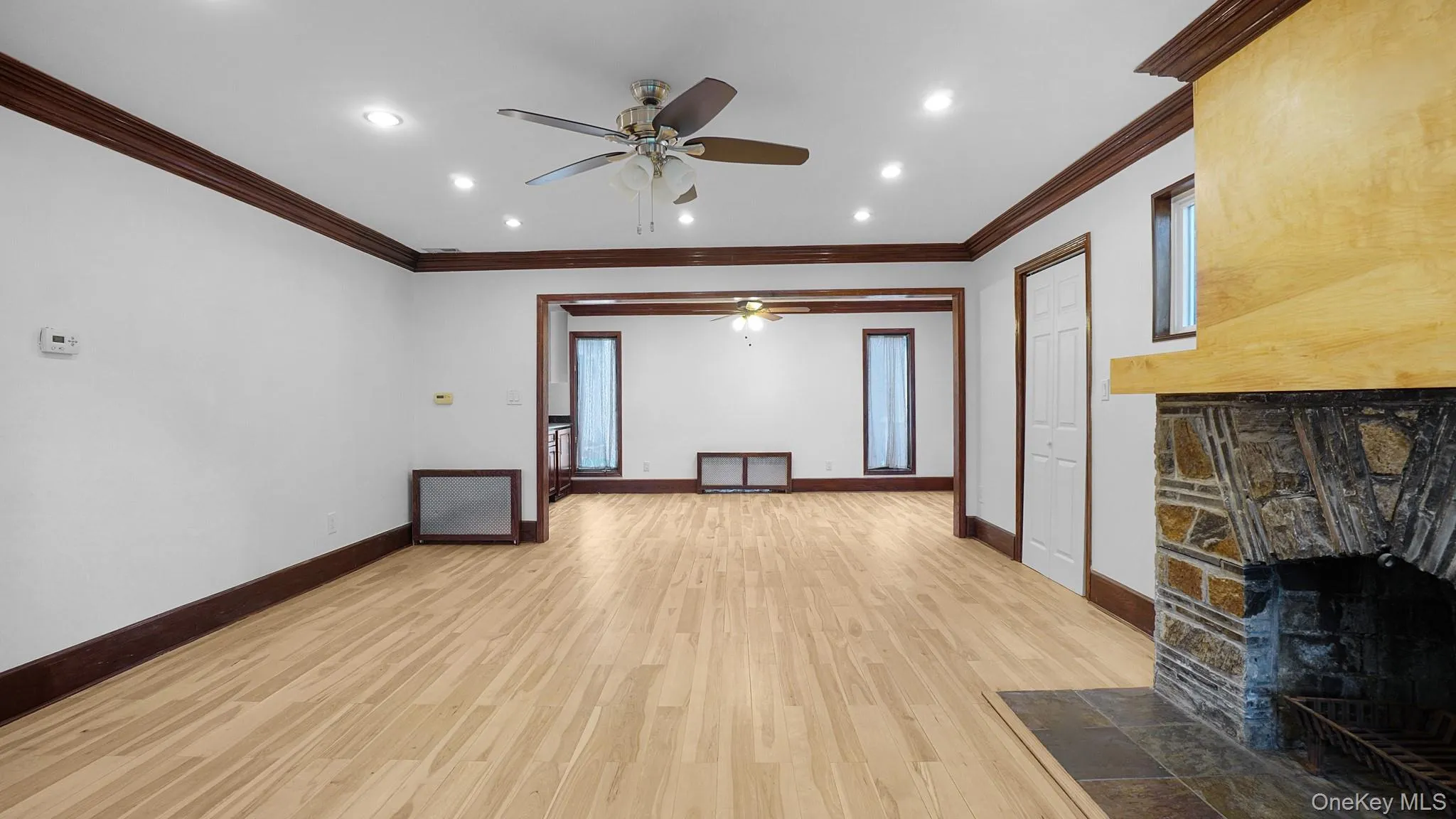 Spacious interior featuring light wood-finish flooring, recessed lighting, and dark wood trim Spacious interior featuring light wood-finish flooring, recessed lighting, and dark wood trim