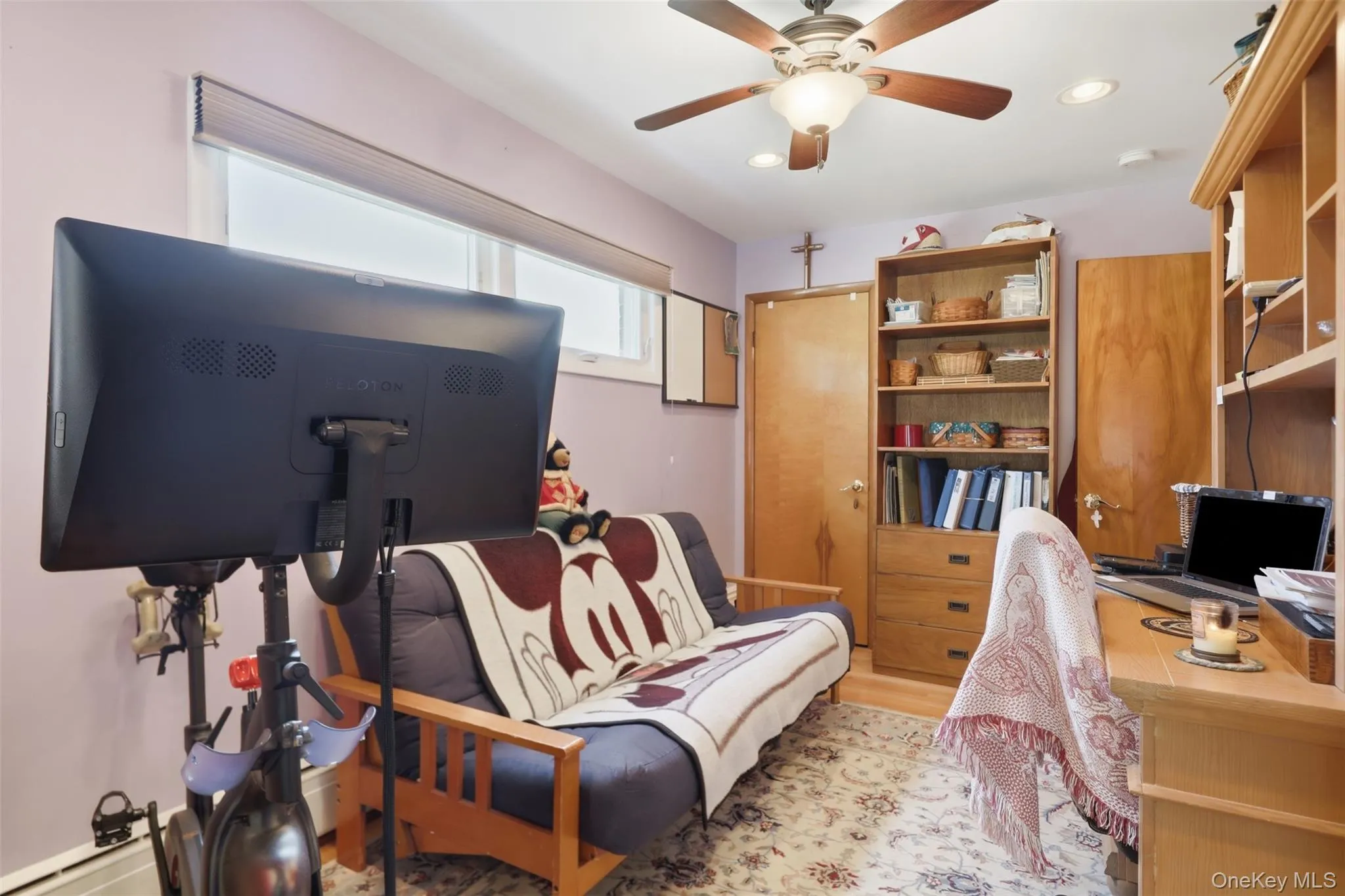 Room featuring light lavender walls and wood-finish flooring Room featuring light lavender walls and wood-finish flooring