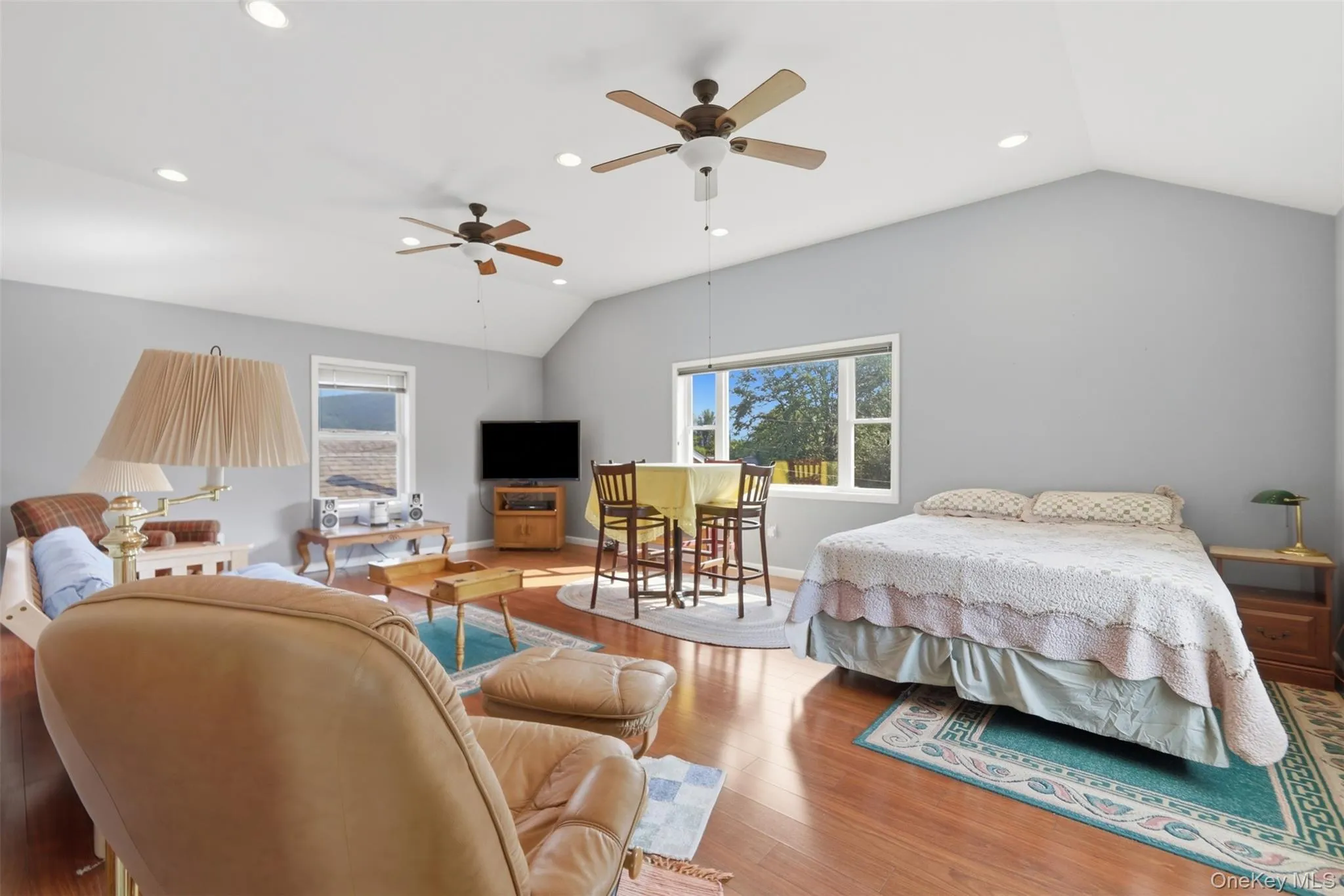 Vaulted ceiling room featuring recessed lighting, wood-finish flooring, and multiple windows Vaulted ceiling room featuring recessed lighting, wood-finish flooring, and multiple windows