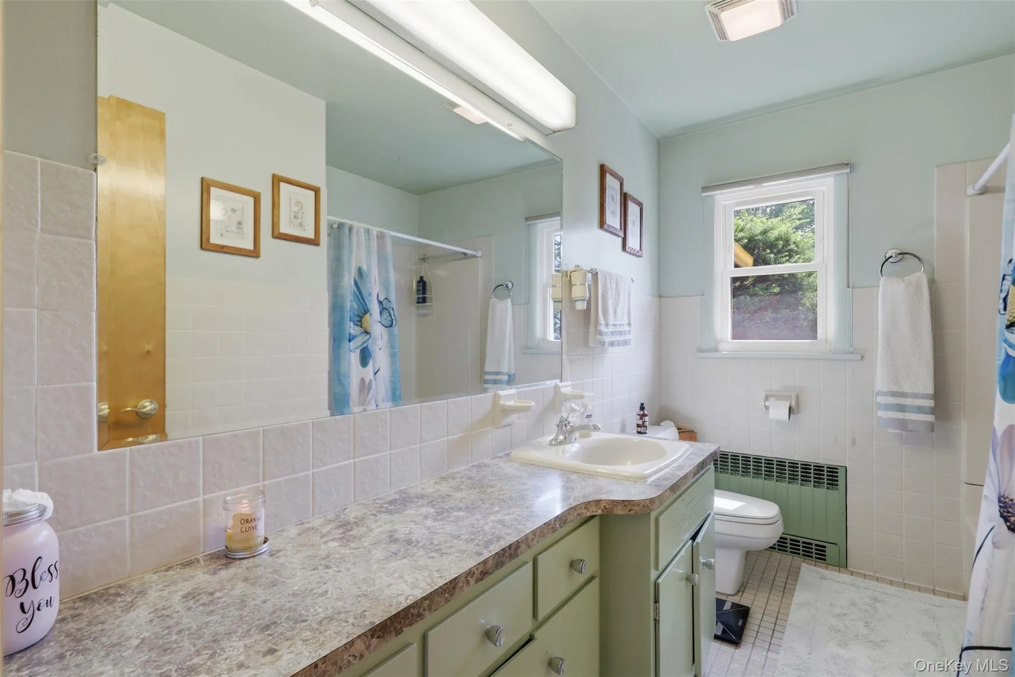 Bathroom featuring a vanity with an integrated sink, patterned countertop, and light green cabinetry Bathroom featuring a vanity with an integrated sink, patterned countertop, and light green cabinetry