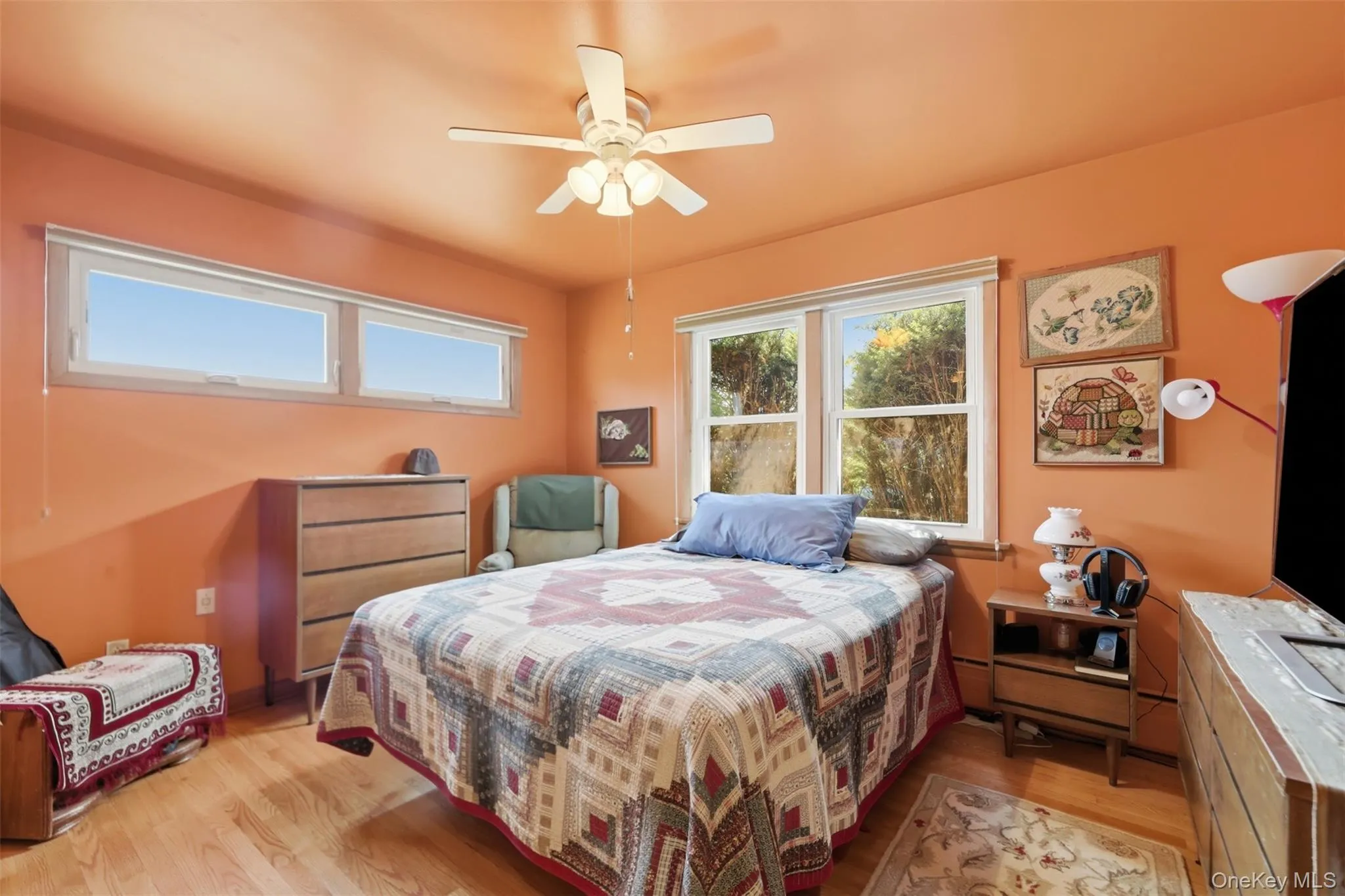 Bedroom featuring wood-finish flooring, a ceiling fan with integrated lighting, and multiple windows Bedroom featuring wood-finish flooring, a ceiling fan with integrated lighting, and multiple windows