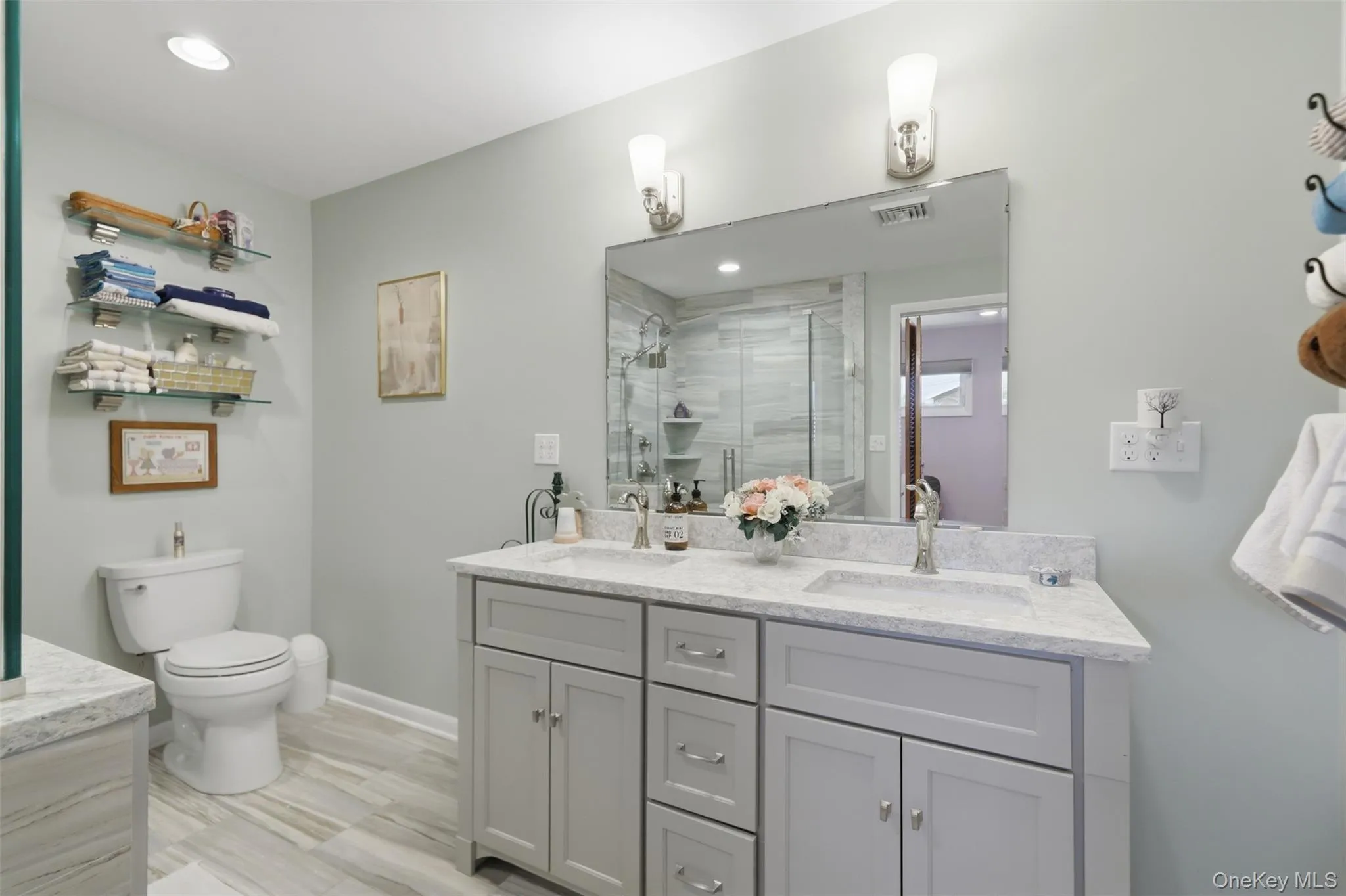 Double vanity with integrated sinks and brushed nickel faucets set in a light-toned countertop Double vanity with integrated sinks and brushed nickel faucets set in a light-toned countertop