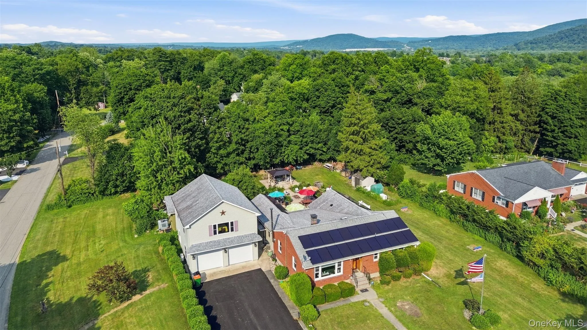 Brick residence featuring solar panels, a gabled roof, and a mature tree-lined setting Brick residence featuring solar panels, a gabled roof, and a mature tree-lined setting