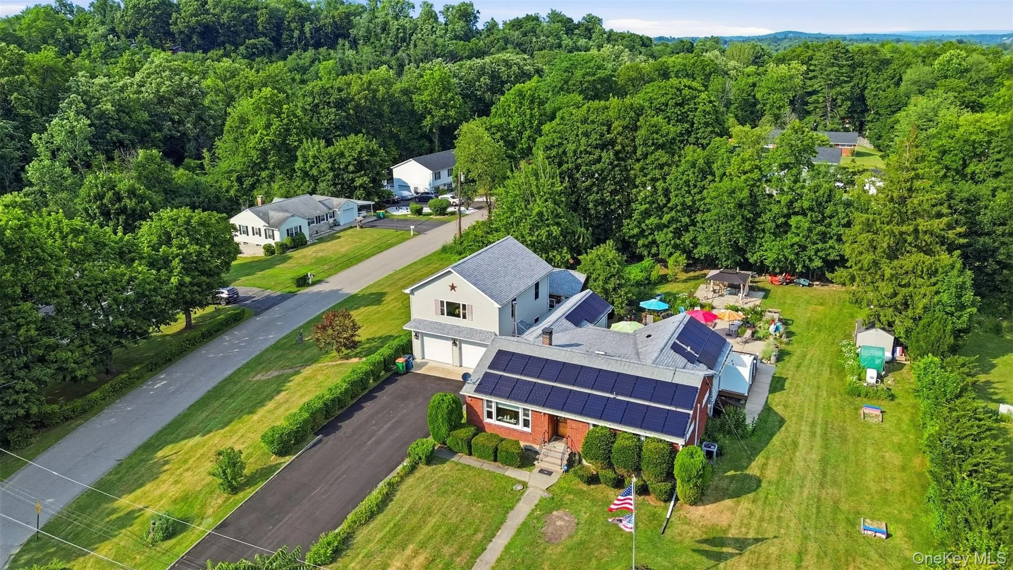 Expansive property featuring a brick and siding exterior, solar panel installation, attached two-car garage, and a substantial green lawn Expansive property featuring a brick and siding exterior, solar panel installation, attached two-car garage, and a substantial green lawn