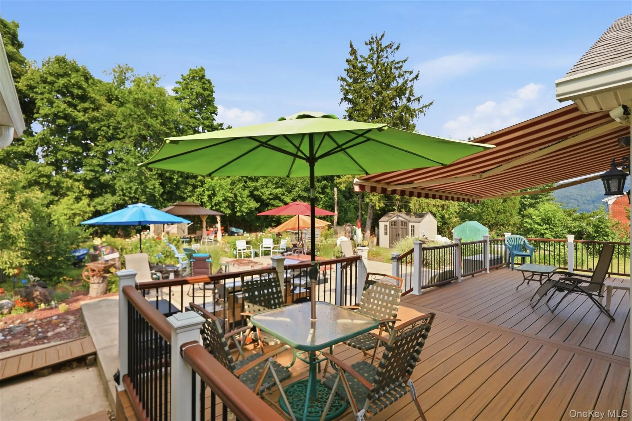 Expansive outdoor deck featuring wood-finish flooring, white railing posts, and black balusters Expansive outdoor deck featuring wood-finish flooring, white railing posts, and black balusters