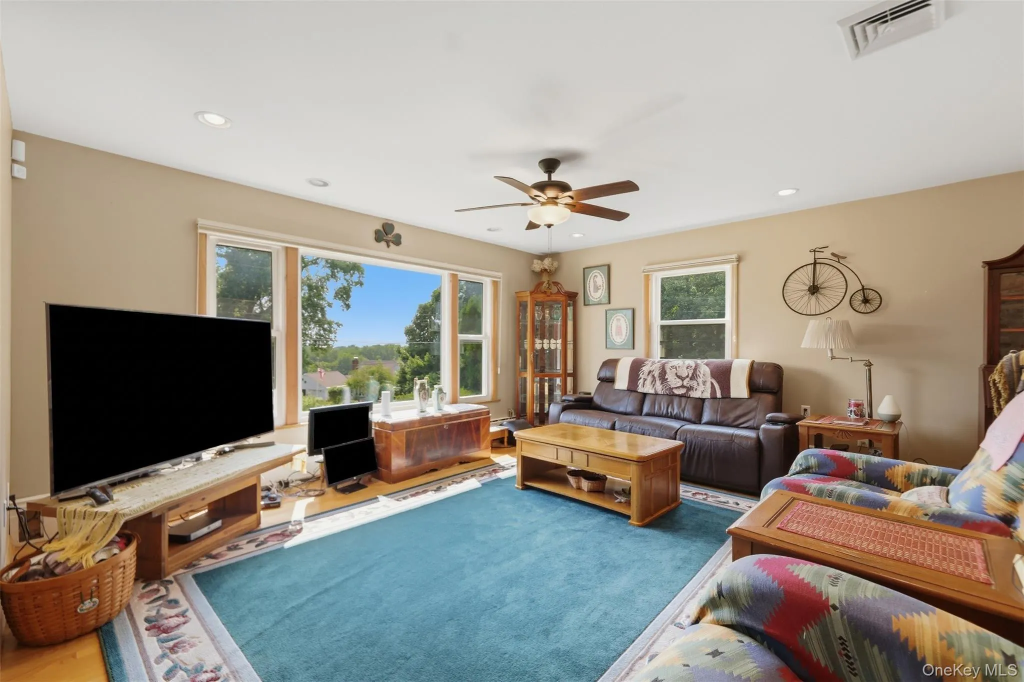 Spacious living area featuring expansive windows, recessed lighting, and a ceiling fan Spacious living area featuring expansive windows, recessed lighting, and a ceiling fan