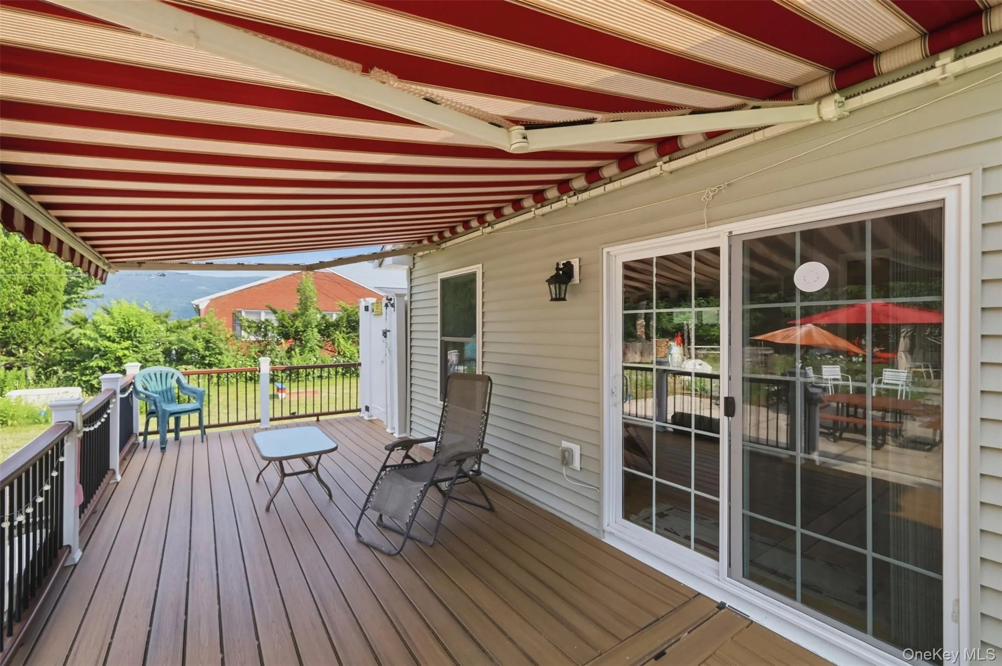 Expansive deck featuring wood-finish flooring and a red and white striped retractable awning Expansive deck featuring wood-finish flooring and a red and white striped retractable awning