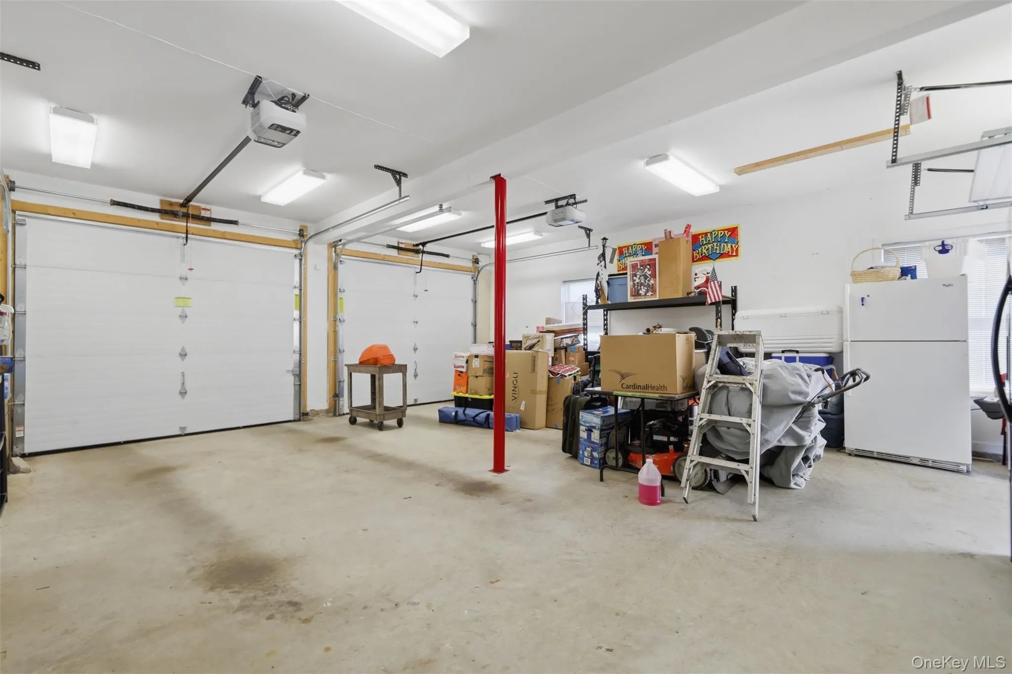 Two-car garage featuring automatic openers, concrete flooring, and fluorescent lighting Two-car garage featuring automatic openers, concrete flooring, and fluorescent lighting