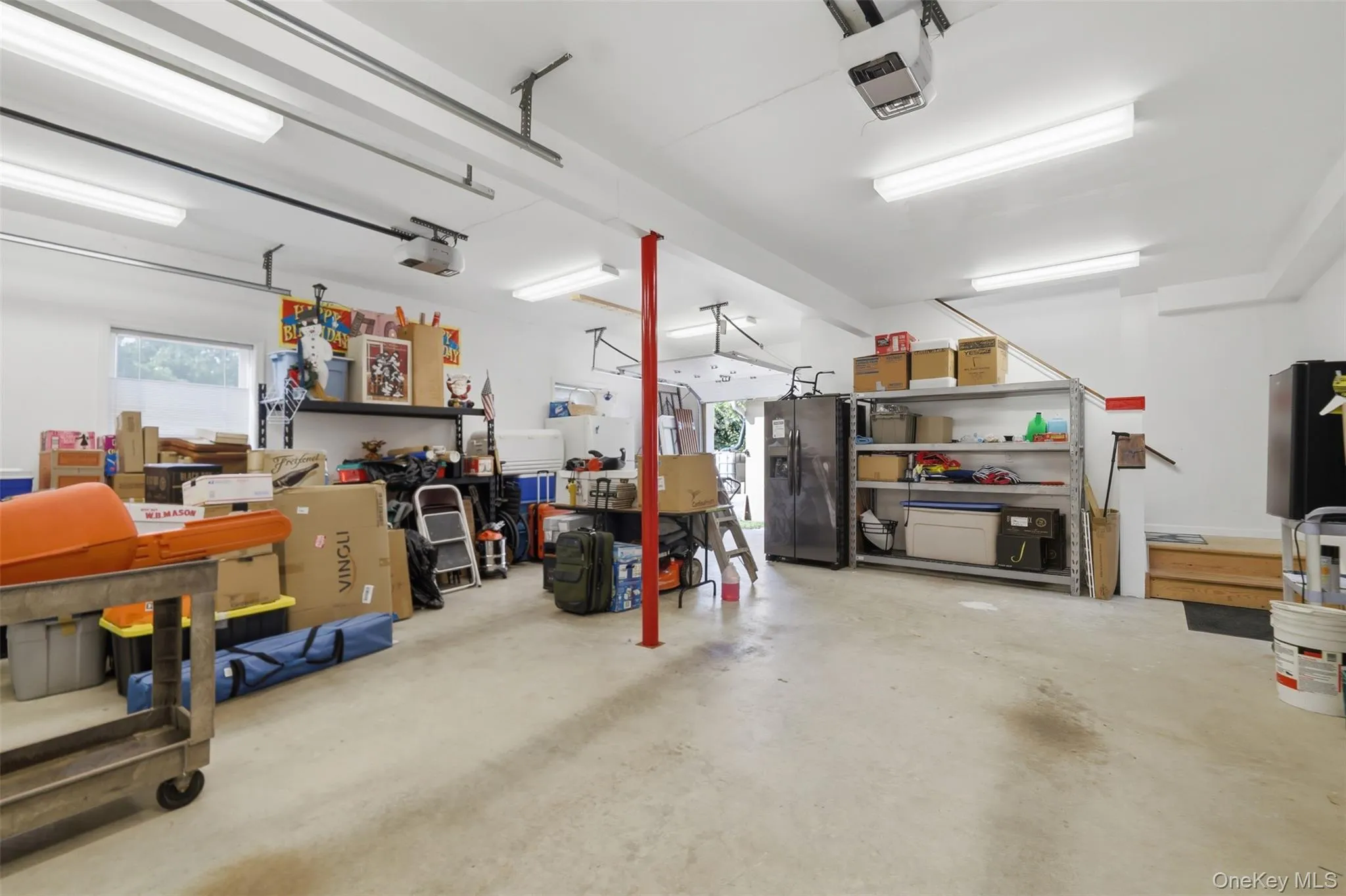 Spacious garage featuring a concrete floor, multiple fluorescent light fixtures, and a large window Spacious garage featuring a concrete floor, multiple fluorescent light fixtures, and a large window