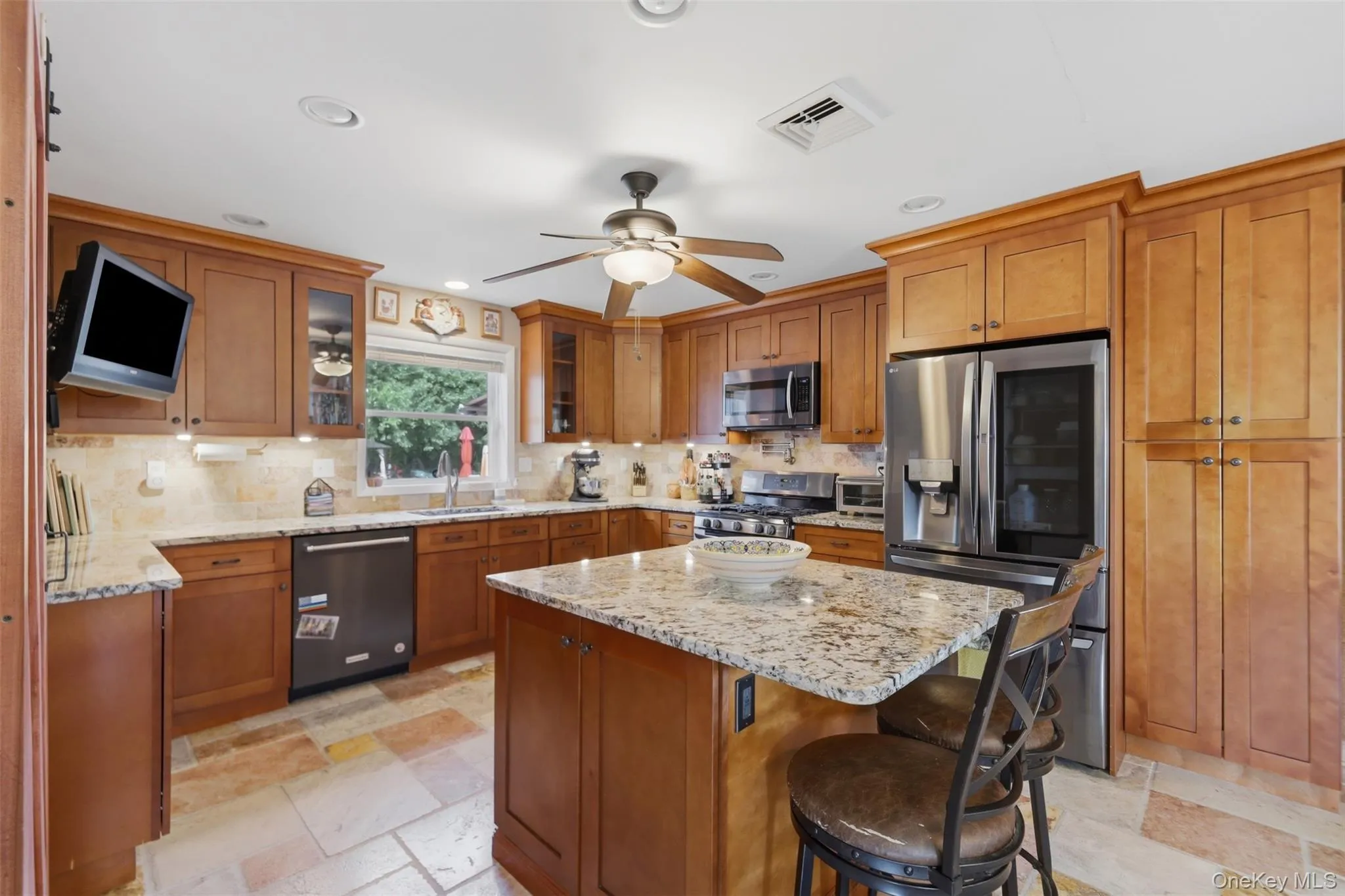 Kitchen featuring an island with a stone countertop, extensive wood cabinetry, stainless steel appliances, tile flooring, and recessed lighting Kitchen featuring an island with a stone countertop, extensive wood cabinetry, stainless steel appliances, tile flooring, and recessed lighting