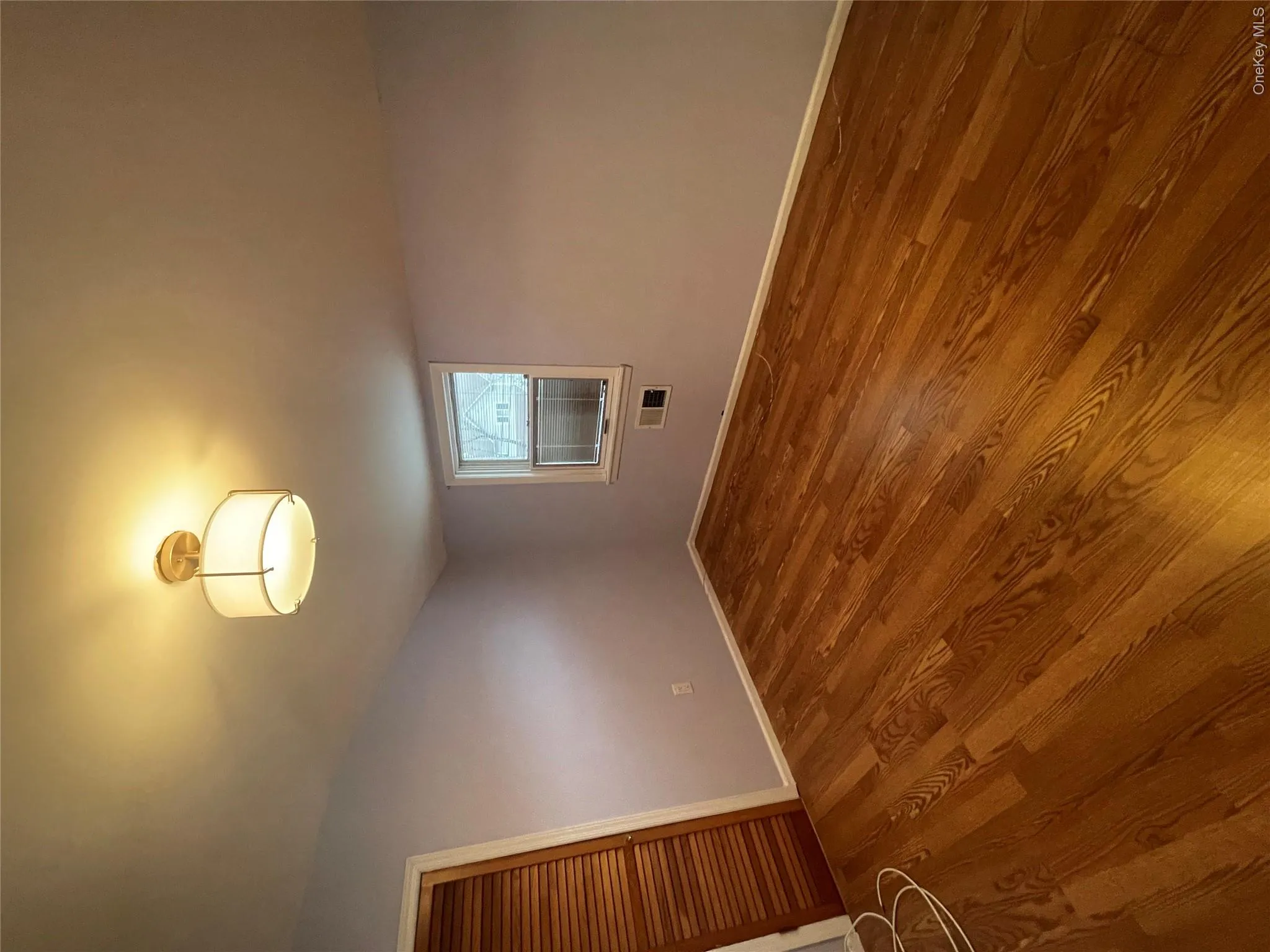 Unfurnished room with wood finished floors, visible vents, and baseboards Unfurnished room with wood finished floors, visible vents, and baseboards