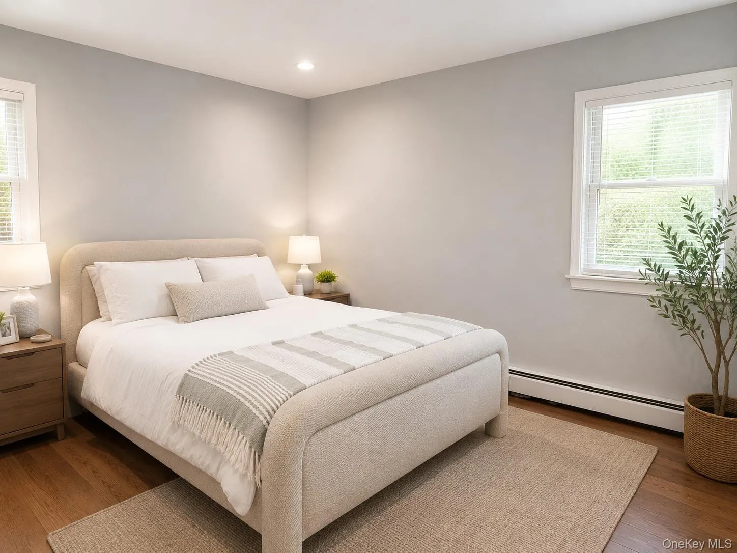 Bedroom featuring wood-finish flooring, two large windows with blinds, recessed lighting, and light gray wall paint Bedroom featuring wood-finish flooring, two large windows with blinds, recessed lighting, and light gray wall paint