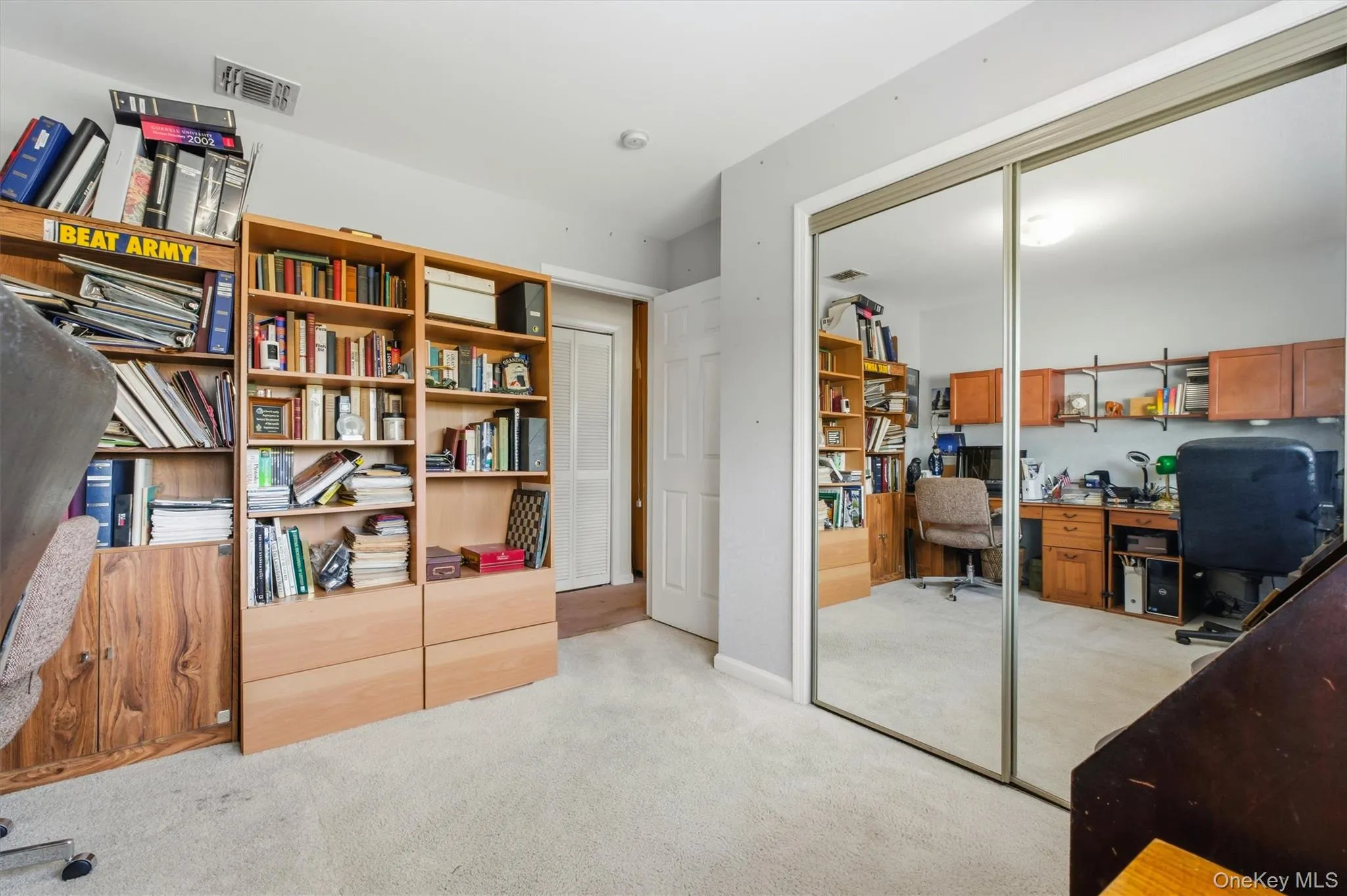 Room featuring mirrored closet doors, light-colored carpeting, recessed lighting, and a white paneled door Room featuring mirrored closet doors, light-colored carpeting, recessed lighting, and a white paneled door