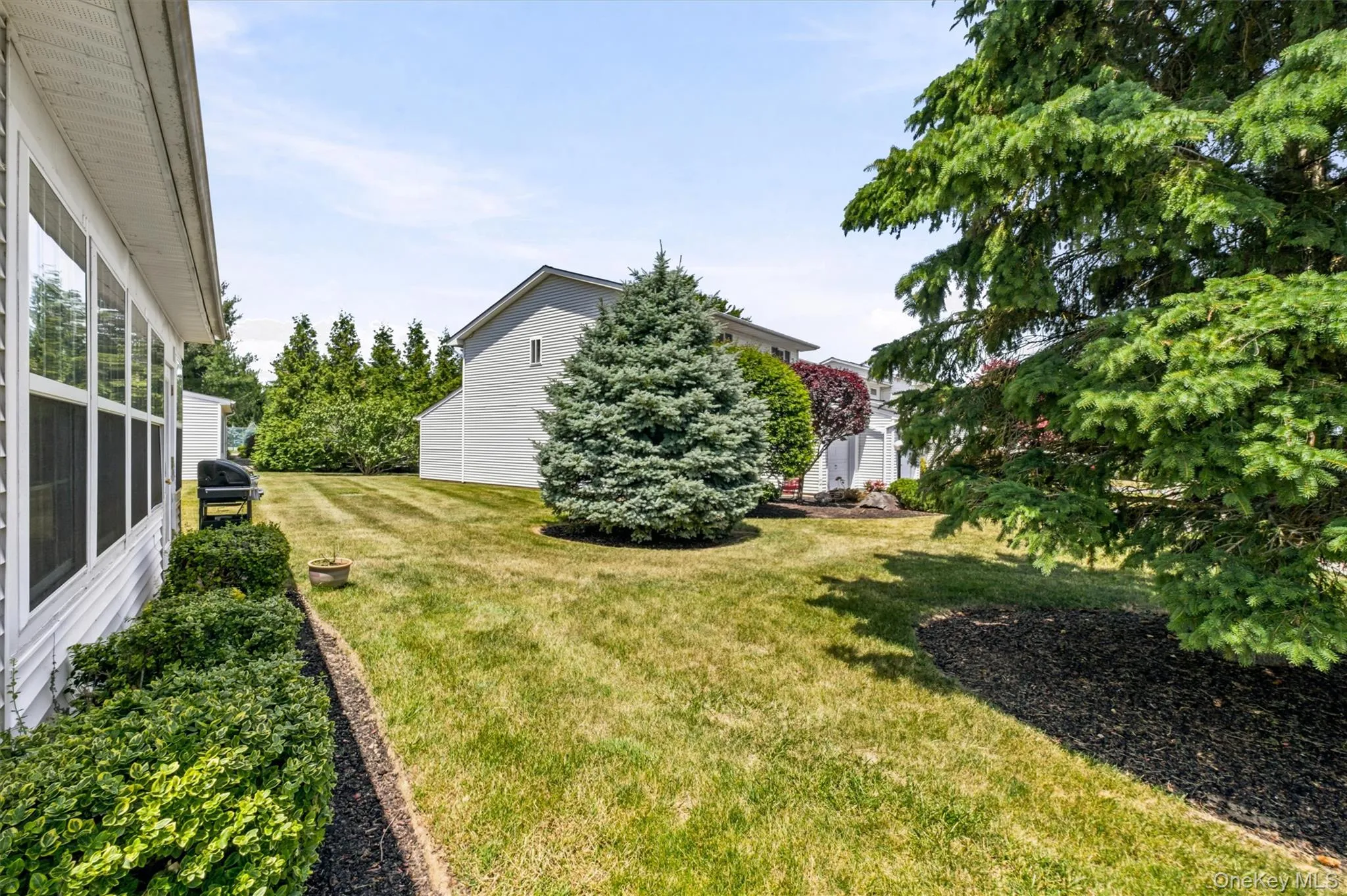 Expansive backyard featuring a manicured lawn, established perimeter landscaping, and mature trees Expansive backyard featuring a manicured lawn, established perimeter landscaping, and mature trees