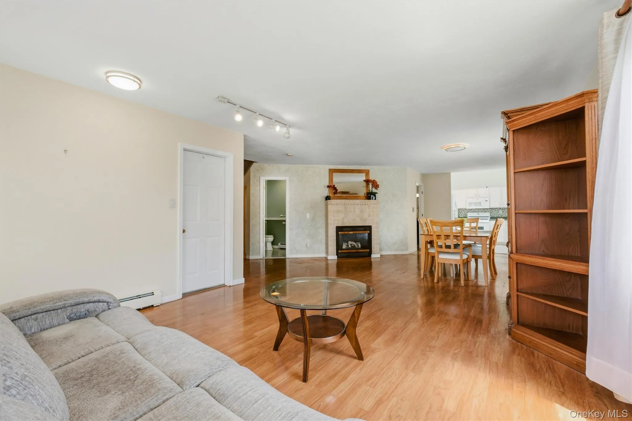 Open concept living space featuring wood-finish flooring, a fireplace with a stone surround and hearth, and recessed lighting Open concept living space featuring wood-finish flooring, a fireplace with a stone surround and hearth, and recessed lighting