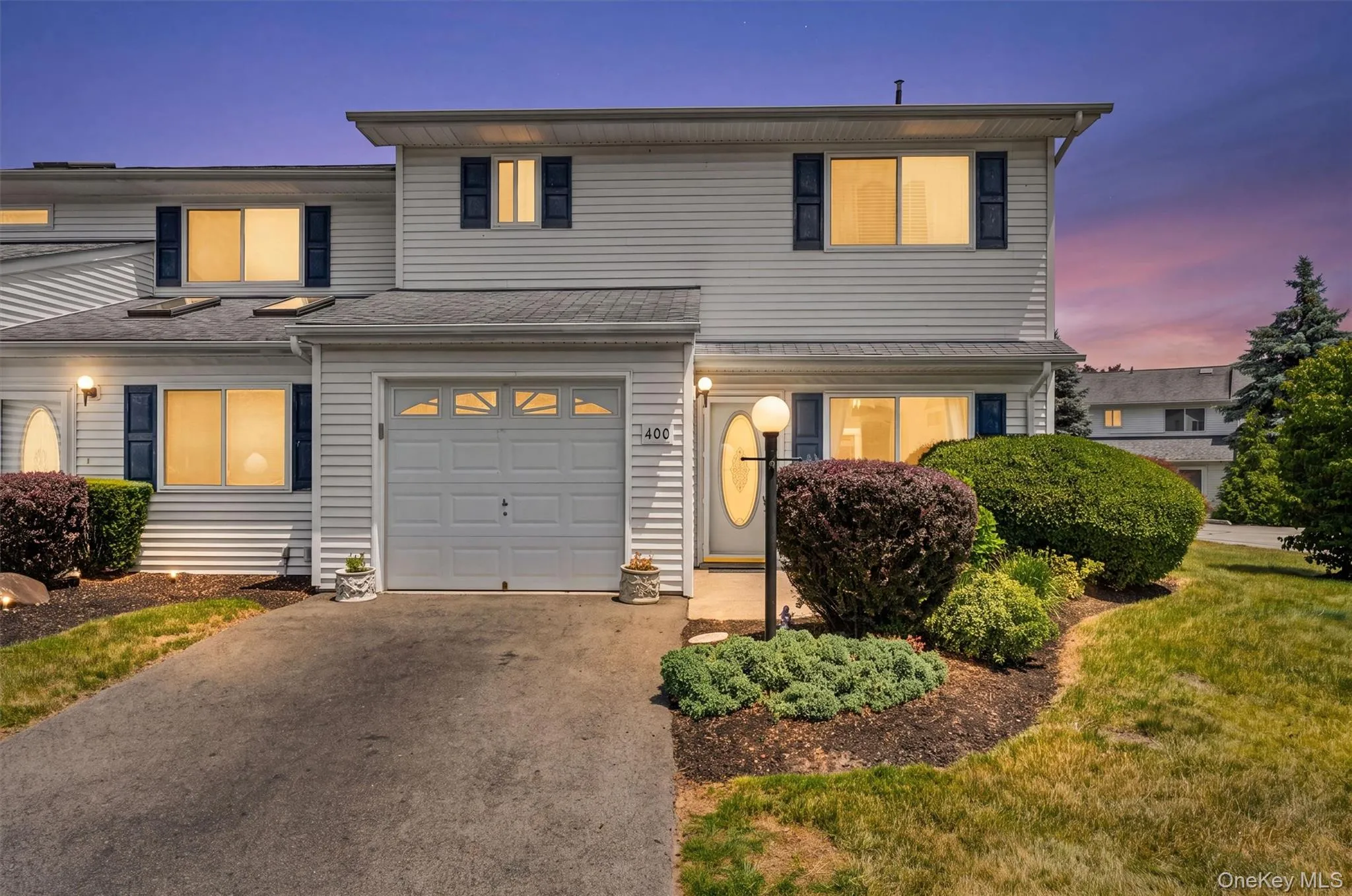 Two-story residence featuring white vinyl siding and dark shutters Two-story residence featuring white vinyl siding and dark shutters