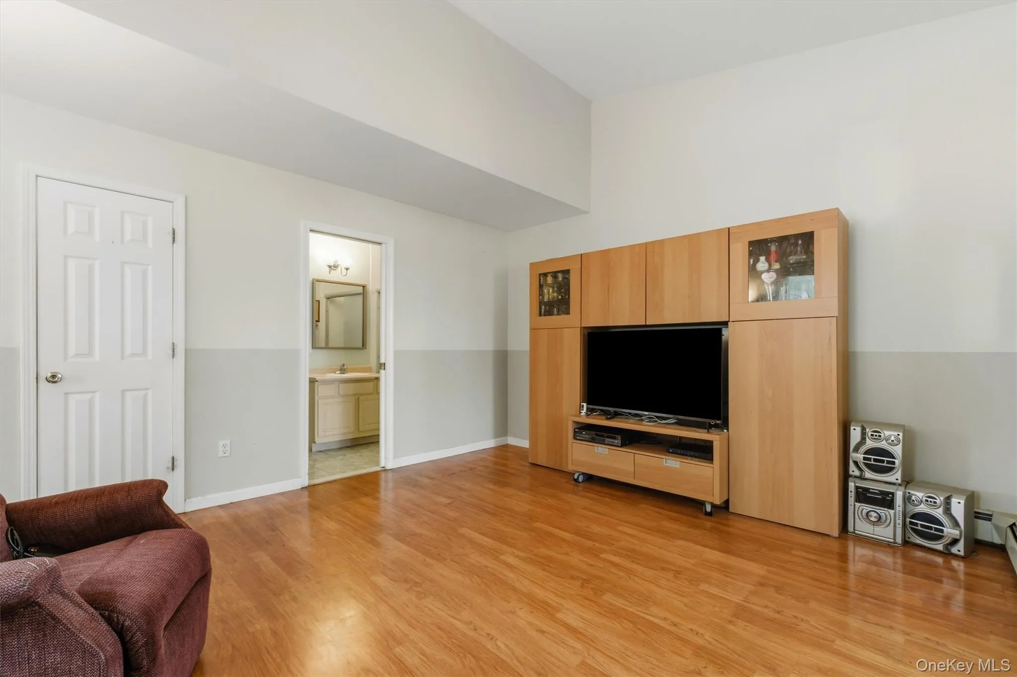 Living area featuring vaulted ceilings, hardwood floors, generous natural light, and an en-suite bath Living area featuring vaulted ceilings, hardwood floors, generous natural light, and an en-suite bath