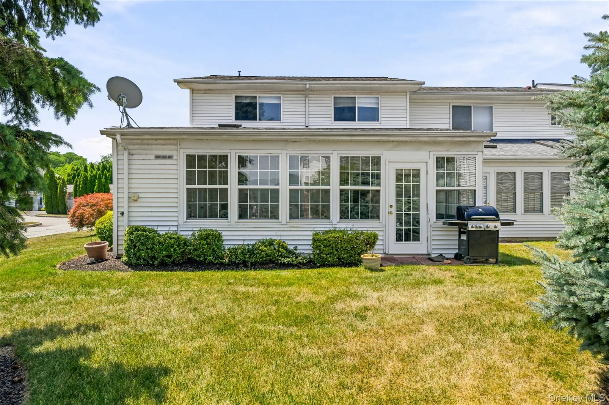 White vinyl siding exterior featuring a sunroom with multiple windows and a glass-paneled door White vinyl siding exterior featuring a sunroom with multiple windows and a glass-paneled door