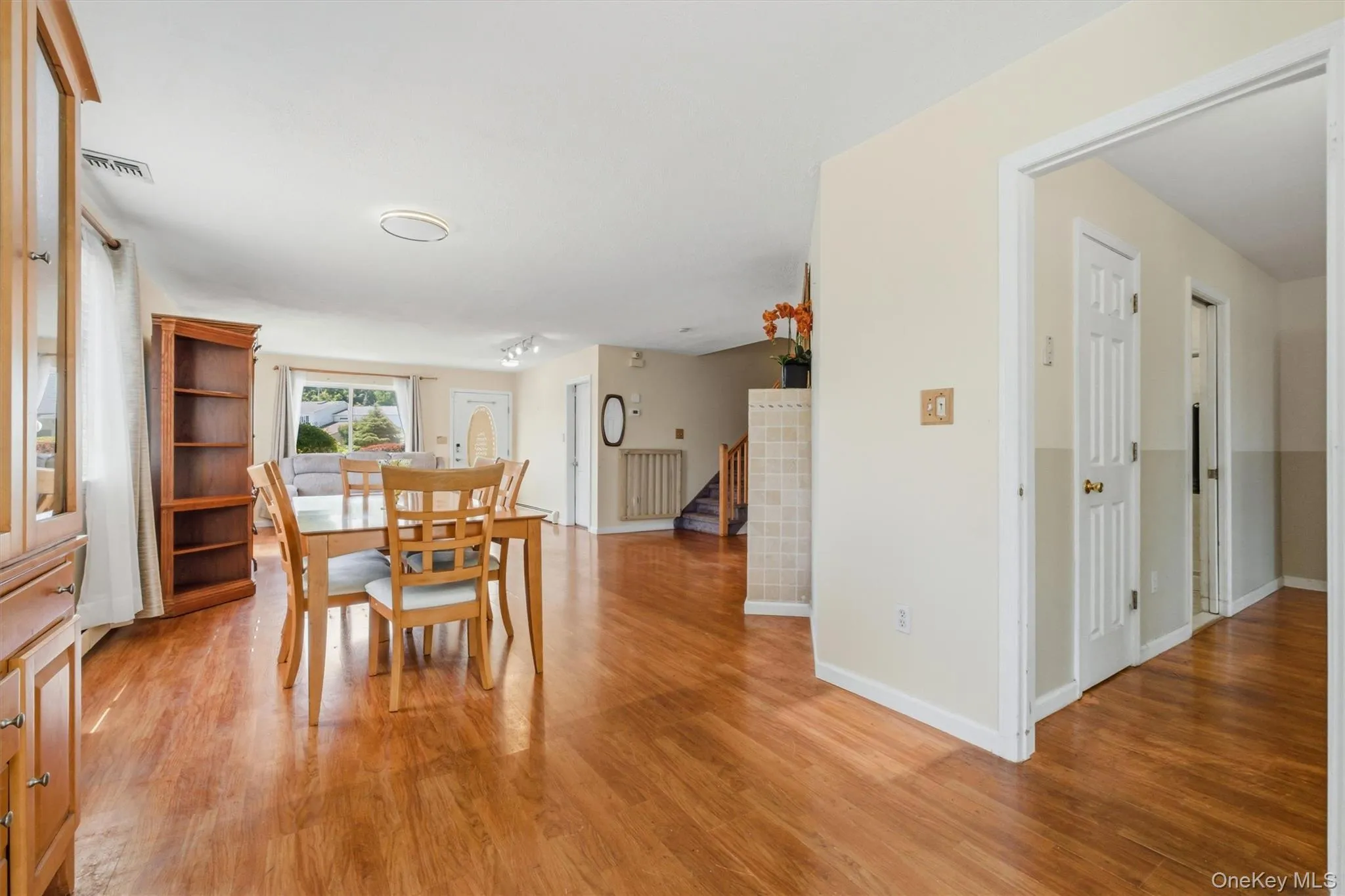 Spacious room featuring wood-finish flooring, light-colored wall paint, and a visible window providing natural illumination Spacious room featuring wood-finish flooring, light-colored wall paint, and a visible window providing natural illumination