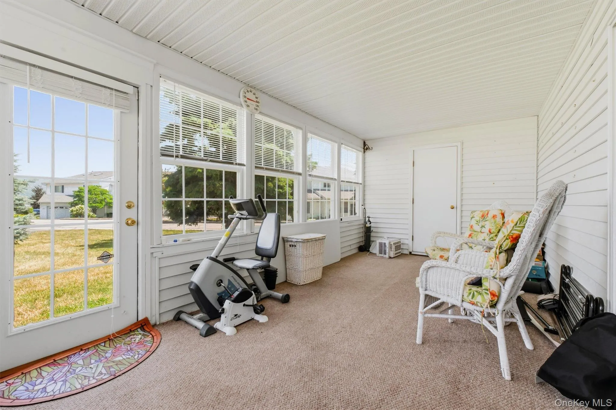 Enclosed porch featuring carpet flooring, horizontal siding walls, a white paneled ceiling, and multiple windows with blinds Enclosed porch featuring carpet flooring, horizontal siding walls, a white paneled ceiling, and multiple windows with blinds