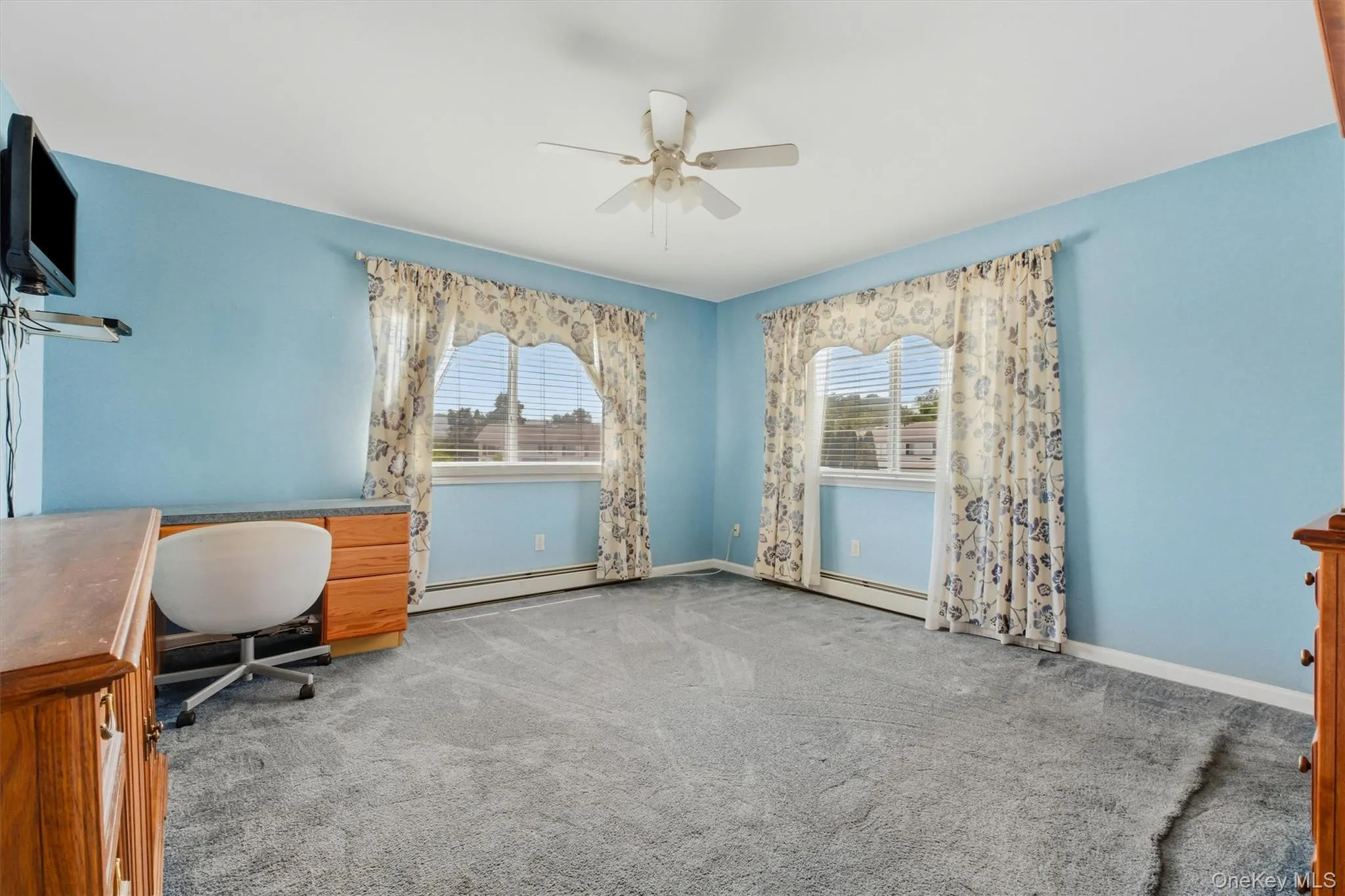 Spacious room featuring light blue walls, gray carpet, and two large windows with horizontal blinds Spacious room featuring light blue walls, gray carpet, and two large windows with horizontal blinds